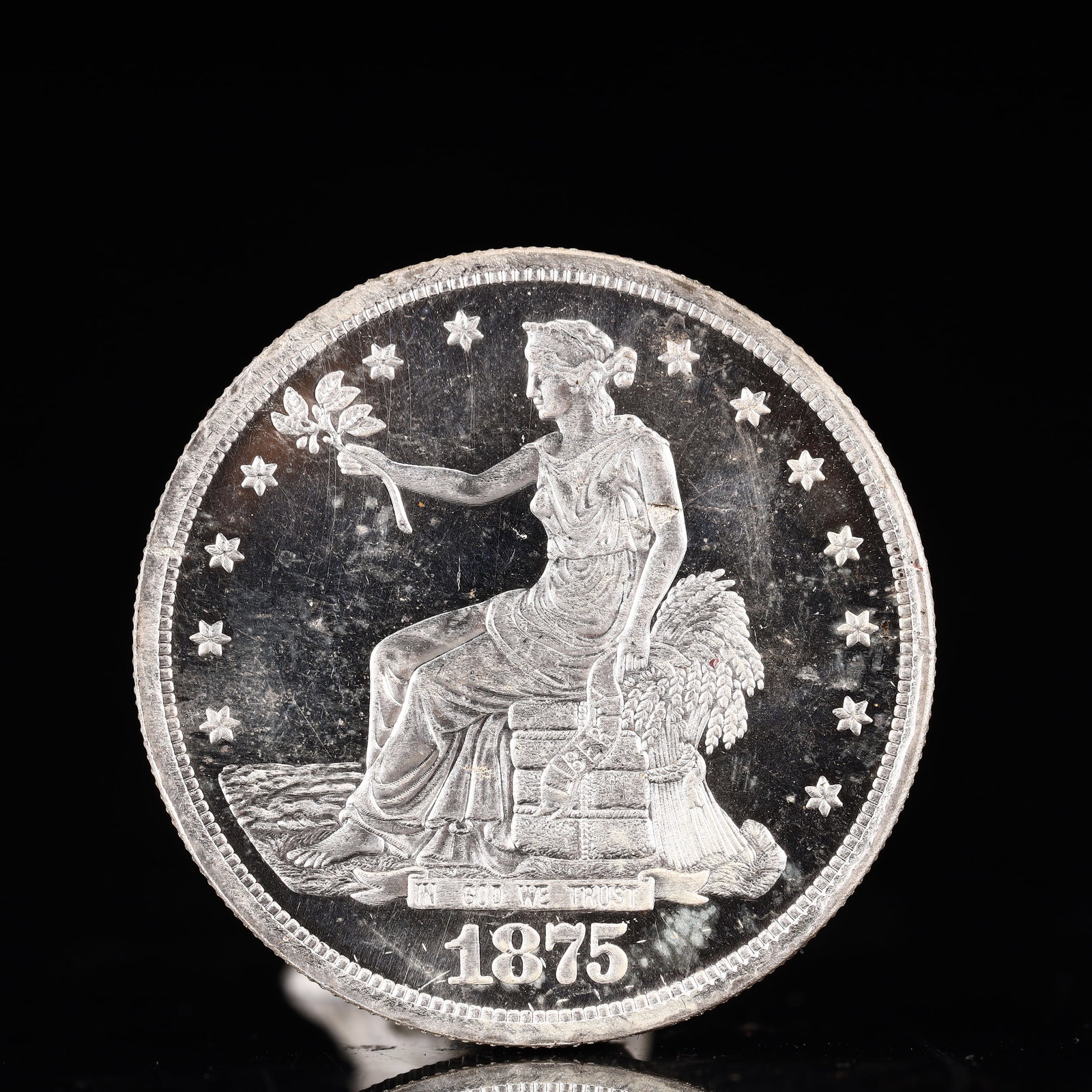 USA Trade Dollar 1875 Coin: American coin. Obverse: Liberty seated on a pedestal facing the sea to the left holding olive branches surrounded by 13 stars. IN GOD WE TRUST / LIBERTY / 1875. Reverse: An eagle holding branches with