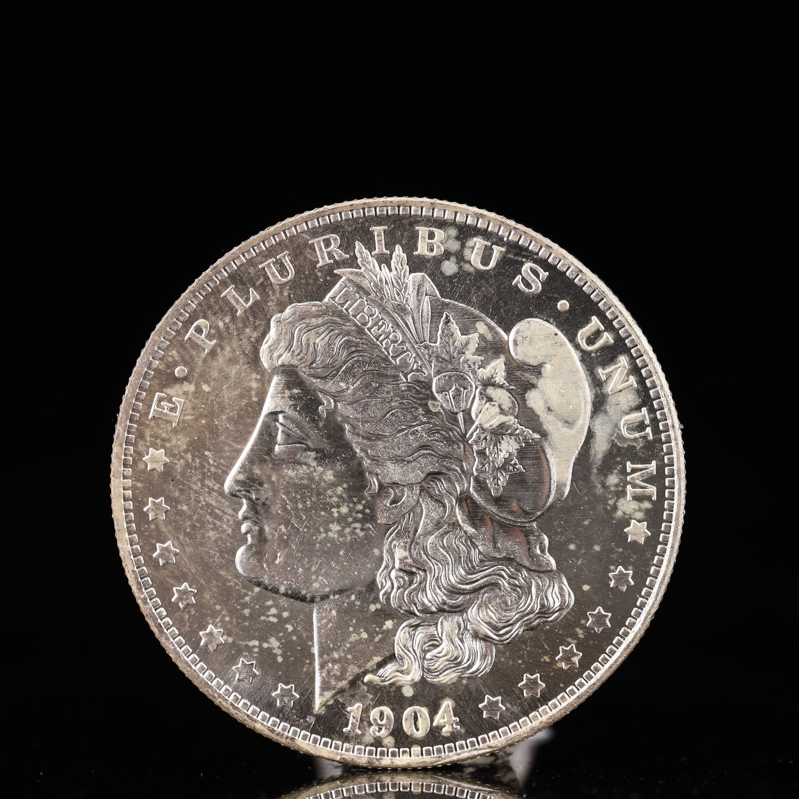 USA Morgan Dollar 1904 Coin: Obv: profile bust with date below and E PLURIBUS UNUM legend and stars around. Rev: eagle with In God we trust above within wreath with UNITED STATES OF AMERICA ONE DOLLAR legend. IN GOD WE TRUST / LI