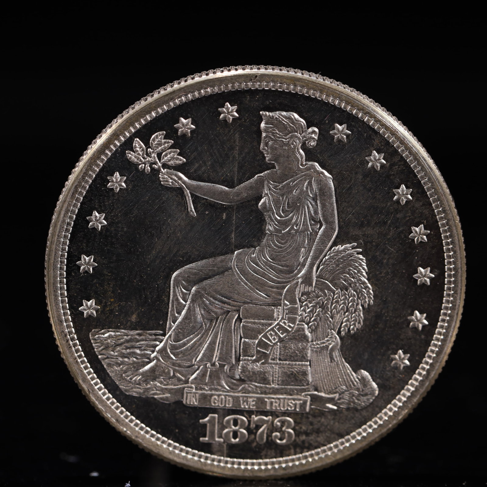 USA Trade Dollar 1873 Coin: American coin. Obverse: Liberty seated on a pedestal facing the sea to the left holding olive branches surrounded by 13 stars. IN GOD WE TRUST / LIBERTY / 1873. Reverse: An eagle holding branches with