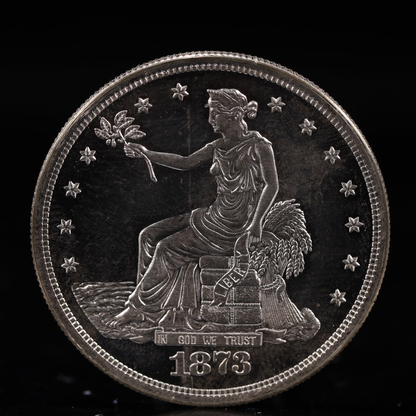 USA Trade Dollar 1873 Coin: American coin. Obverse: Liberty seated on a pedestal facing the sea to the left holding olive branches surrounded by 13 stars. IN GOD WE TRUST / LIBERTY / 1873. Reverse: An eagle holding branches with
