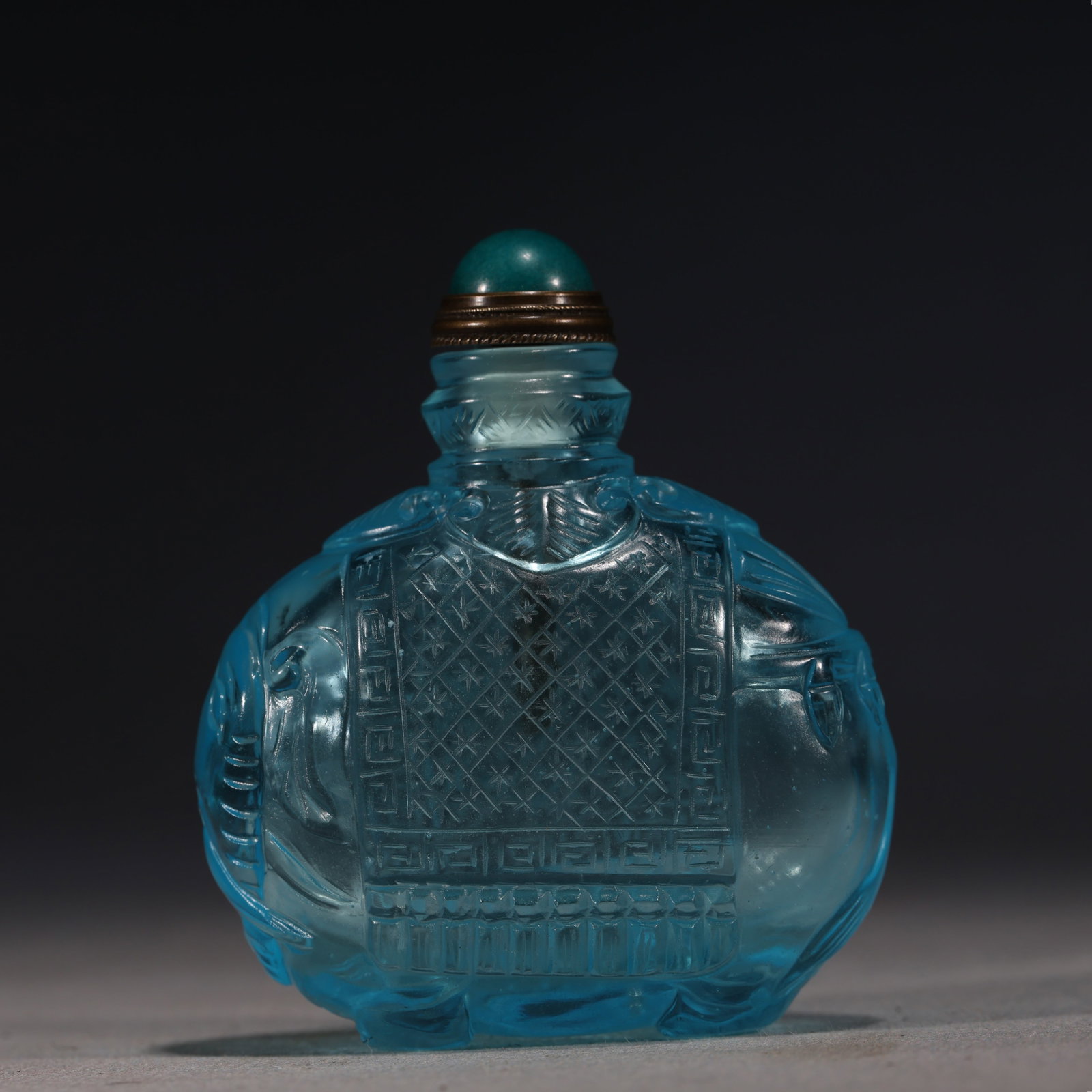 A Chinese Blue Glass Snuff Bottle with Diaper Pattern,Qianlong Mark: A Chinese pale blue glass snuff bottle of rounded form,the front decorated with a panel containing a star diapered ground within key-fret borders,the sides carved with further geometric ornaments,set