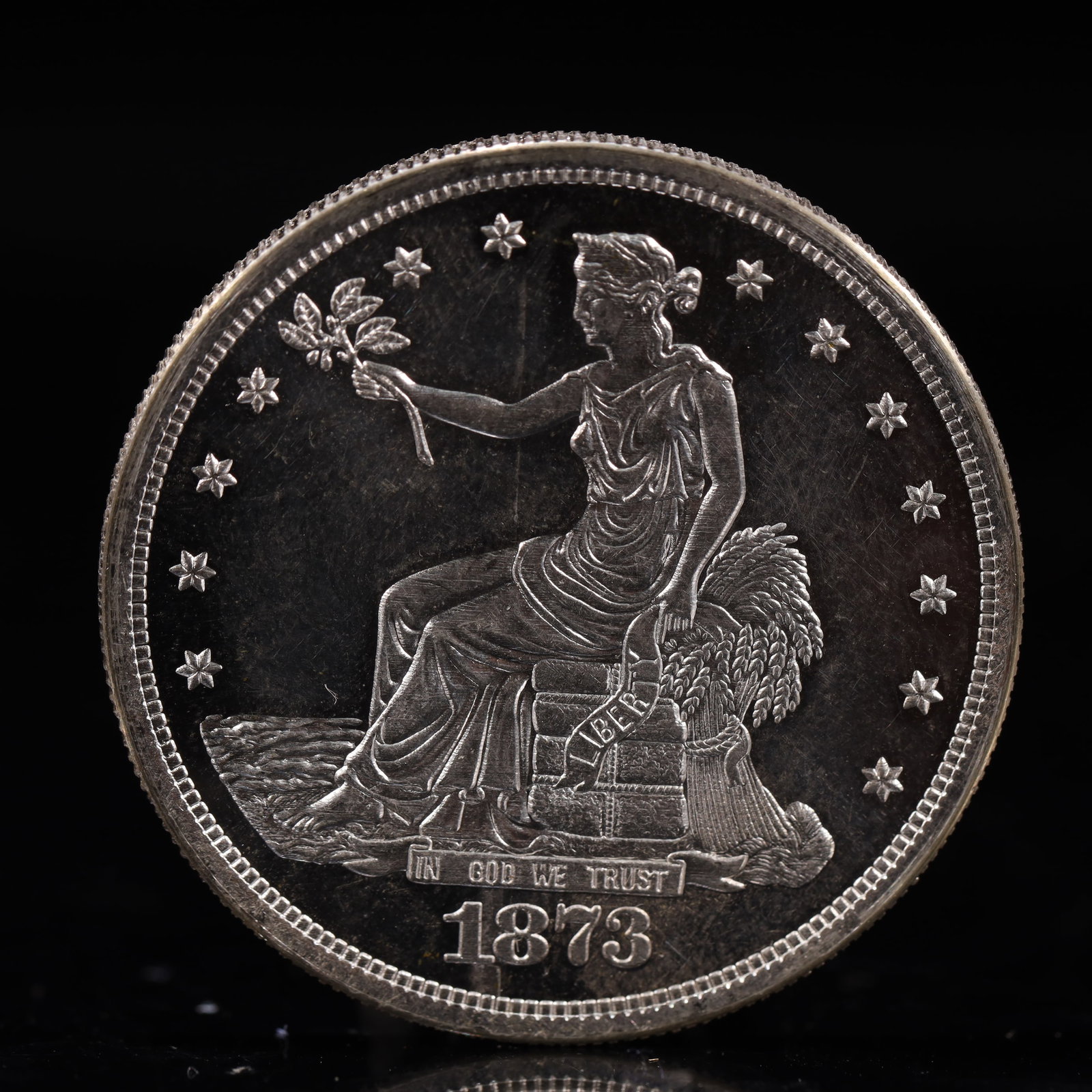 USA Trade Dollar 1873 Coin: American coin. Obverse: Liberty seated on a pedestal facing the sea to the left holding olive branches surrounded by 13 stars. IN GOD WE TRUST / LIBERTY / 1873. Reverse: An eagle holding branches with