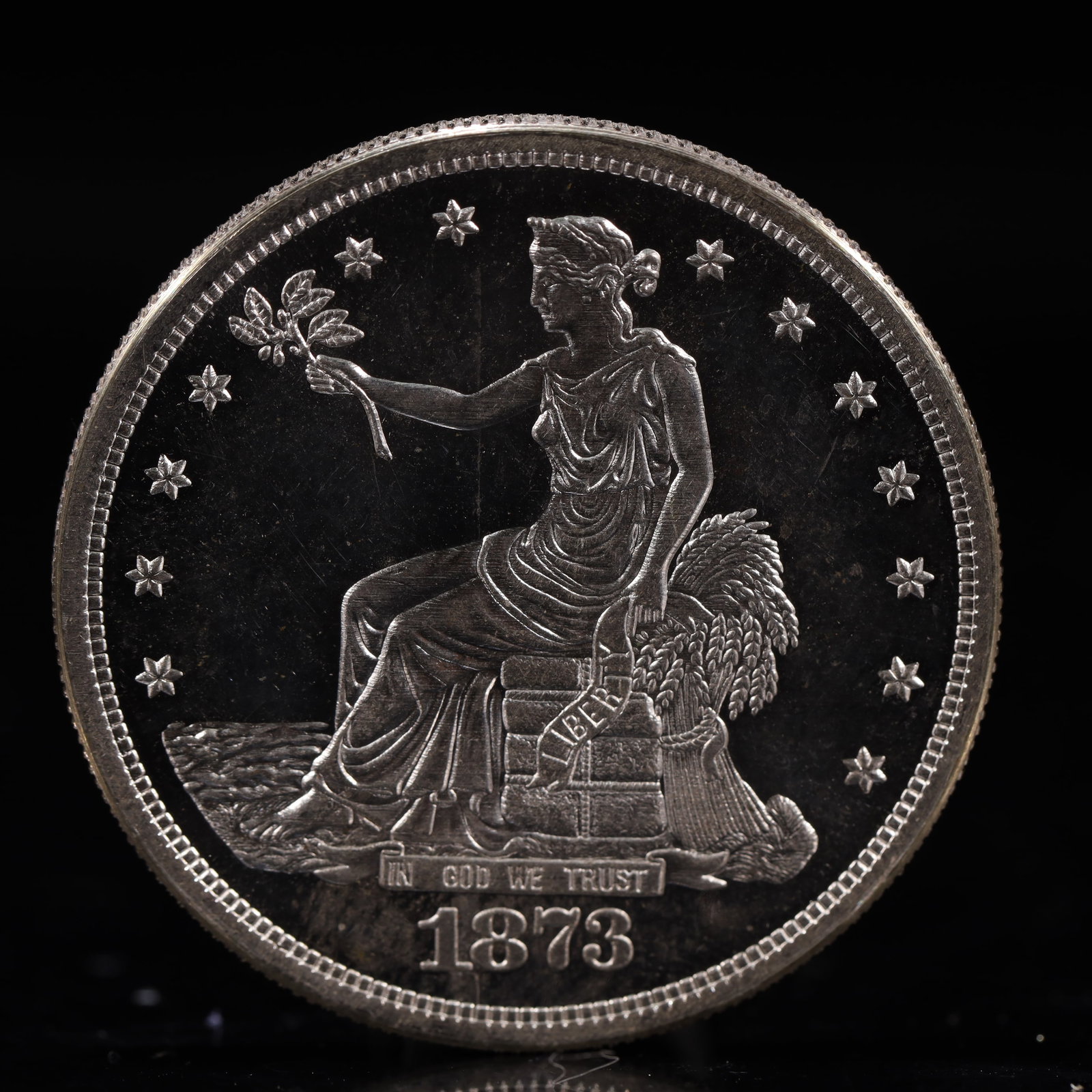 USA Trade Dollar 1873 Coin: American coin. Obverse: Liberty seated on a pedestal facing the sea to the left holding olive branches surrounded by 13 stars. IN GOD WE TRUST / LIBERTY / 1873. Reverse: An eagle holding branches with