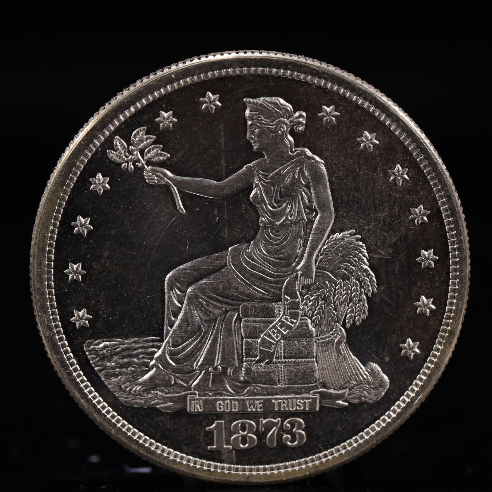 USA Trade Dollar 1873 Coin: American coin. Obverse: Liberty seated on a pedestal facing the sea to the left holding olive branches surrounded by 13 stars. IN GOD WE TRUST / LIBERTY / 1873. Reverse: An eagle holding branches with