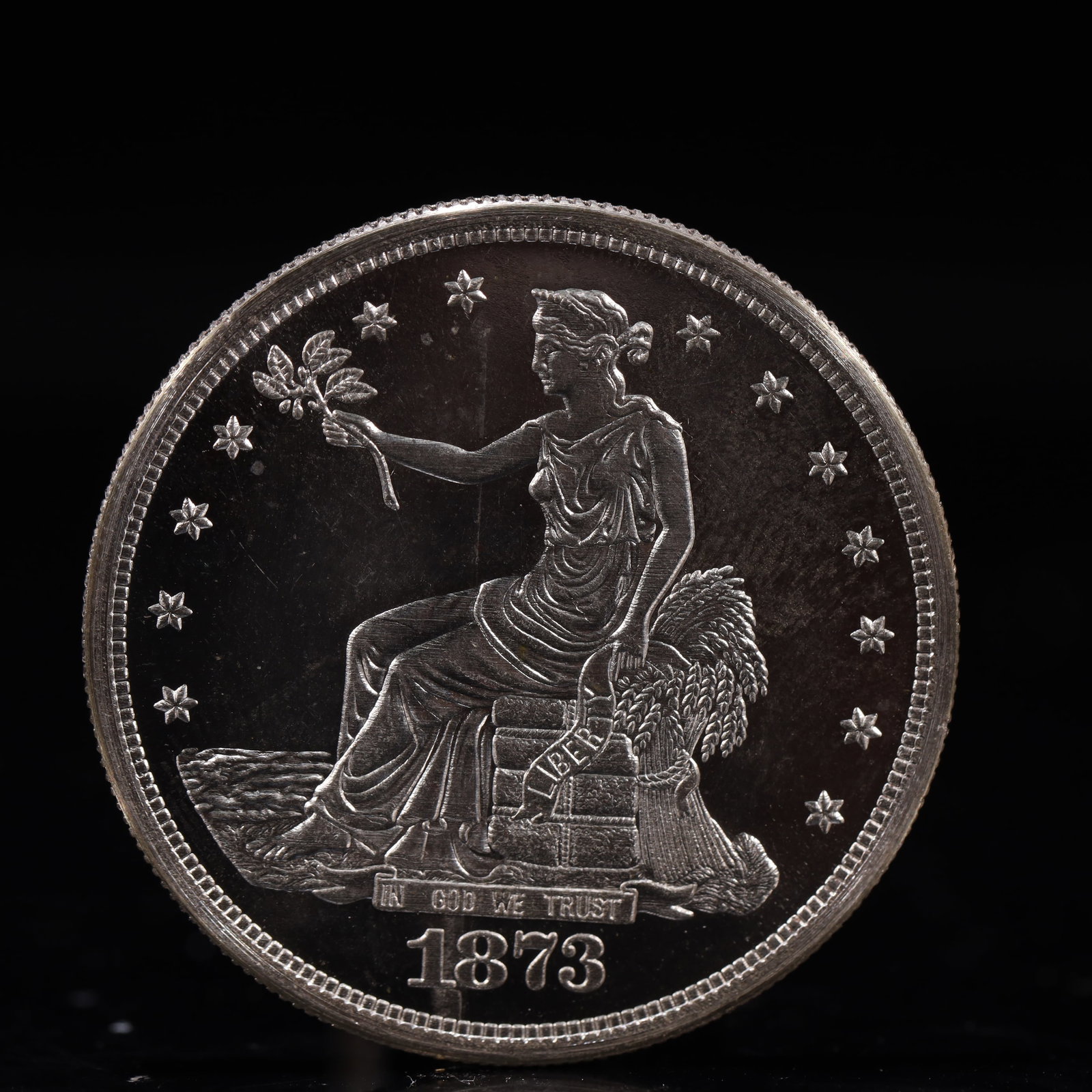 USA Trade Dollar 1873 Coin: American coin. Obverse: Liberty seated on a pedestal facing the sea to the left holding olive branches surrounded by 13 stars. IN GOD WE TRUST / LIBERTY / 1873. Reverse: An eagle holding branches with