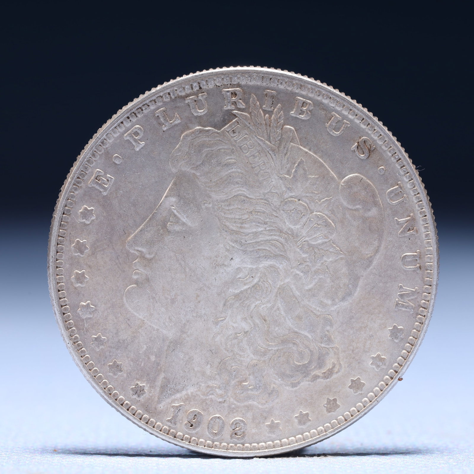 USA Morgan Dollar 1902 Coin: Obv: profile bust with date below and E PLURIBUS UNUM legend and stars around. Rev: eagle with In God we trust above within wreath with UNITED STATES OF AMERICA ONE DOLLAR legend. IN GOD WE TRUST / LI