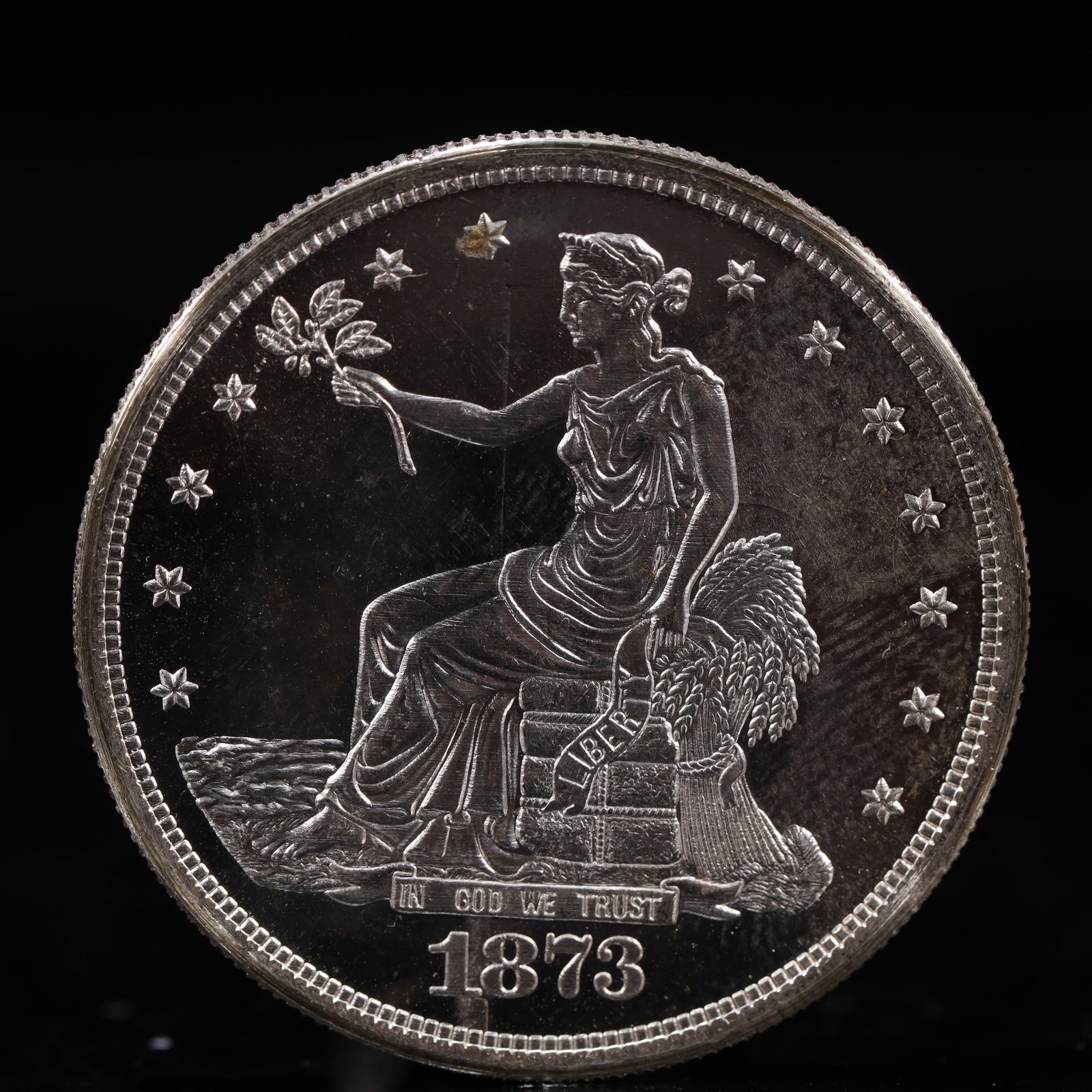 USA Trade Dollar 1873 Coin: American coin. Obverse: Liberty seated on a pedestal facing the sea to the left holding olive branches surrounded by 13 stars. IN GOD WE TRUST / LIBERTY / 1873. Reverse: An eagle holding branches with
