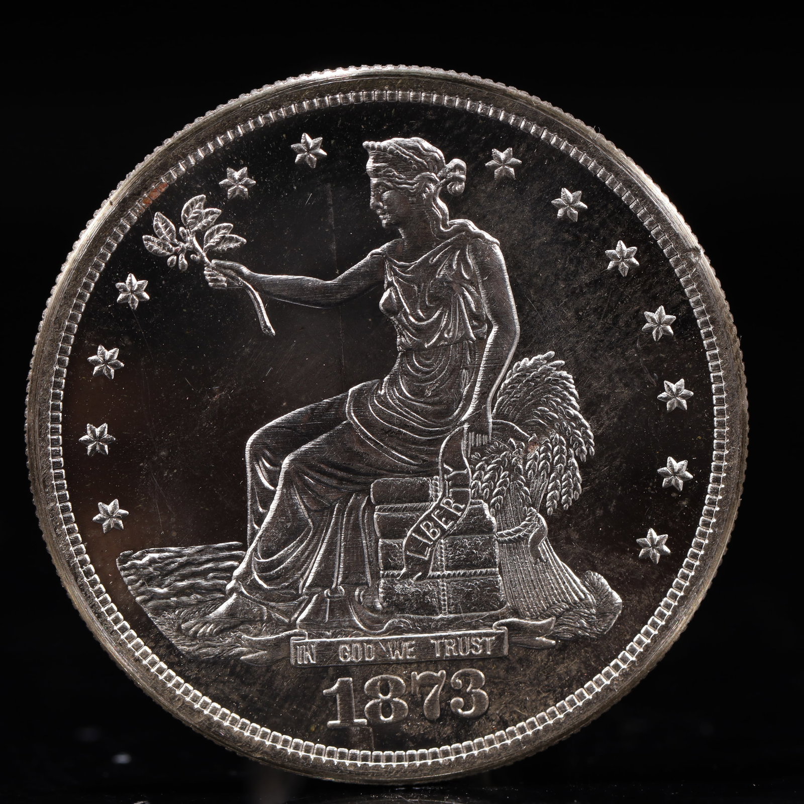 USA Trade Dollar 1873 Coin: American coin. Obverse: Liberty seated on a pedestal facing the sea to the left holding olive branches surrounded by 13 stars. IN GOD WE TRUST / LIBERTY / 1873. Reverse: An eagle holding branches with