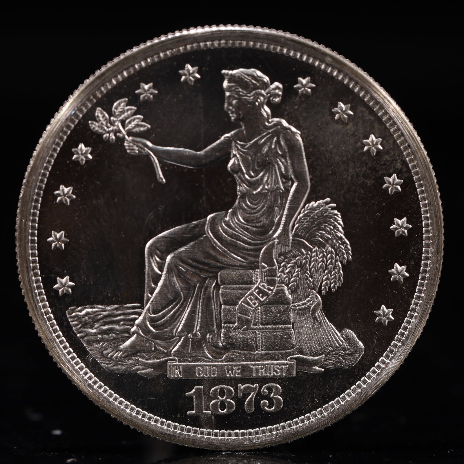 USA Trade Dollar 1873 Coin: American coin. Obverse: Liberty seated on a pedestal facing the sea to the left holding olive branches surrounded by 13 stars. IN GOD WE TRUST / LIBERTY / 1873. Reverse: An eagle holding branches with