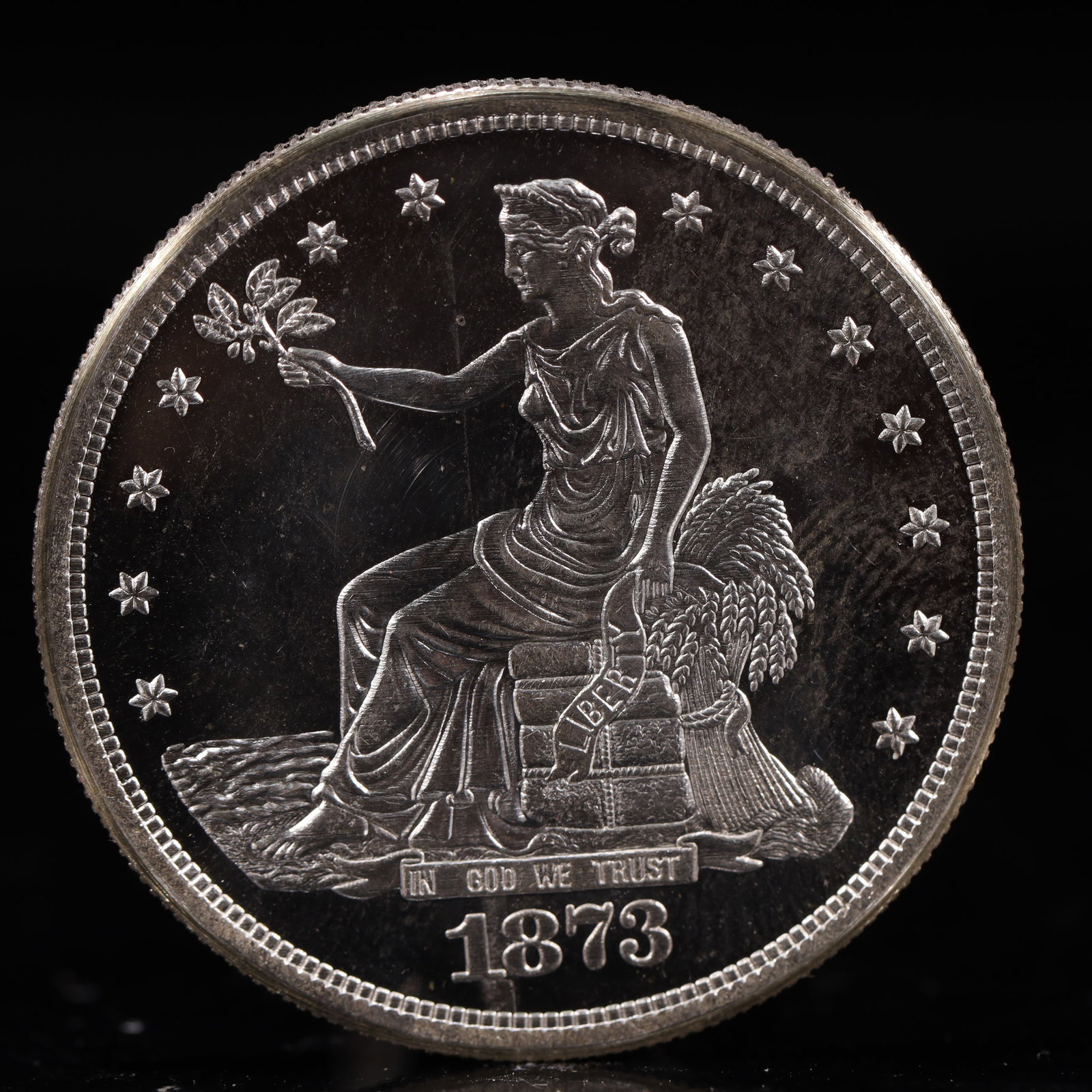 USA Trade Dollar 1873 Coin: American coin. Obverse: Liberty seated on a pedestal facing the sea to the left holding olive branches surrounded by 13 stars. IN GOD WE TRUST / LIBERTY / 1873. Reverse: An eagle holding branches with