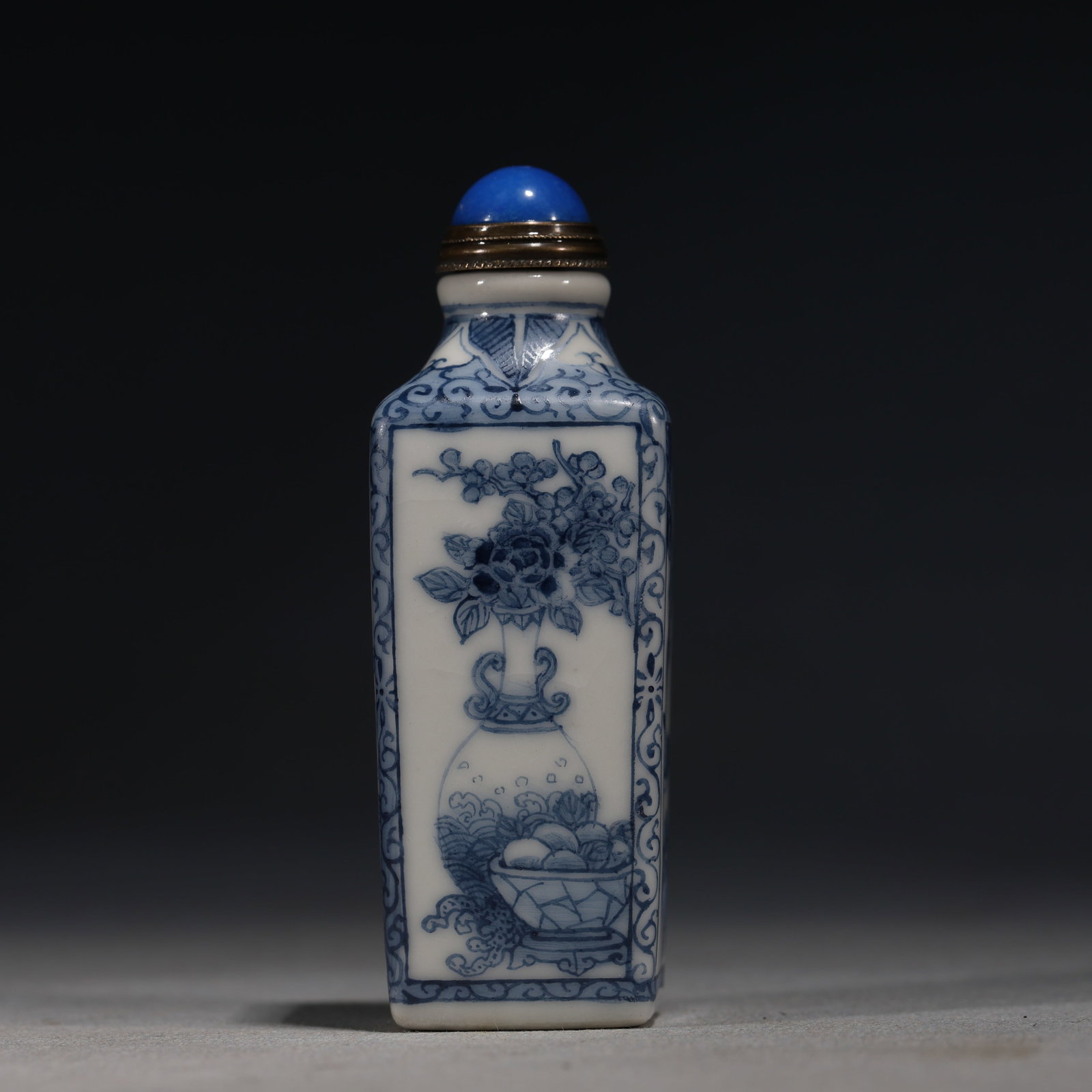 A Chinese Blue and White Porcelain Square Snuff Bottle with Antique Objects and Birds,Qianlong Mark: A blue and white porcelain snuff bottle of square form,painted on one side with an antique vase holding flowers and on the other with a bird on a flowering branch,within key-fret borders.Fitted with a