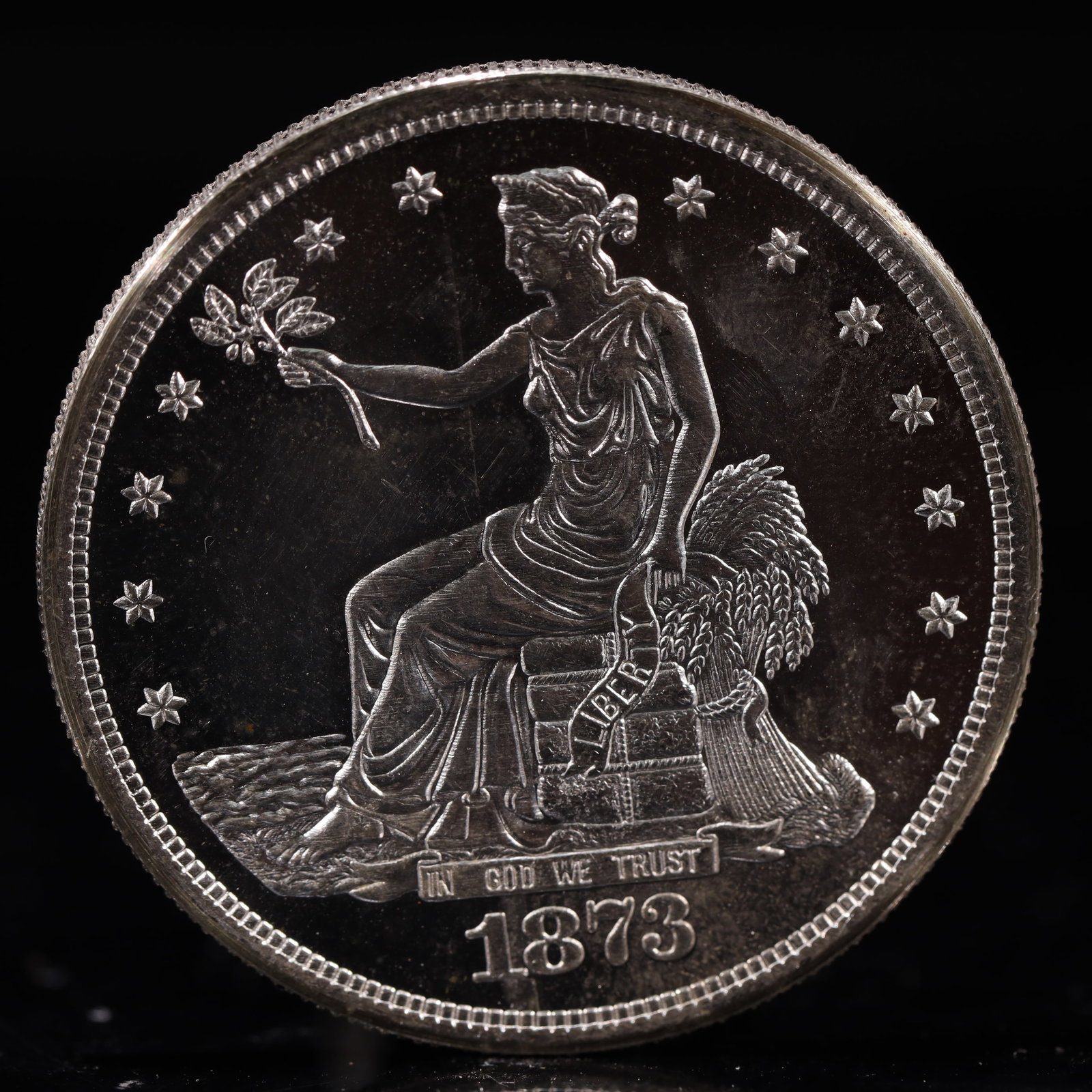 USA Trade Dollar 1873 Coin: American coin. Obverse: Liberty seated on a pedestal facing the sea to the left holding olive branches surrounded by 13 stars. IN GOD WE TRUST / LIBERTY / 1873. Reverse: An eagle holding branches with