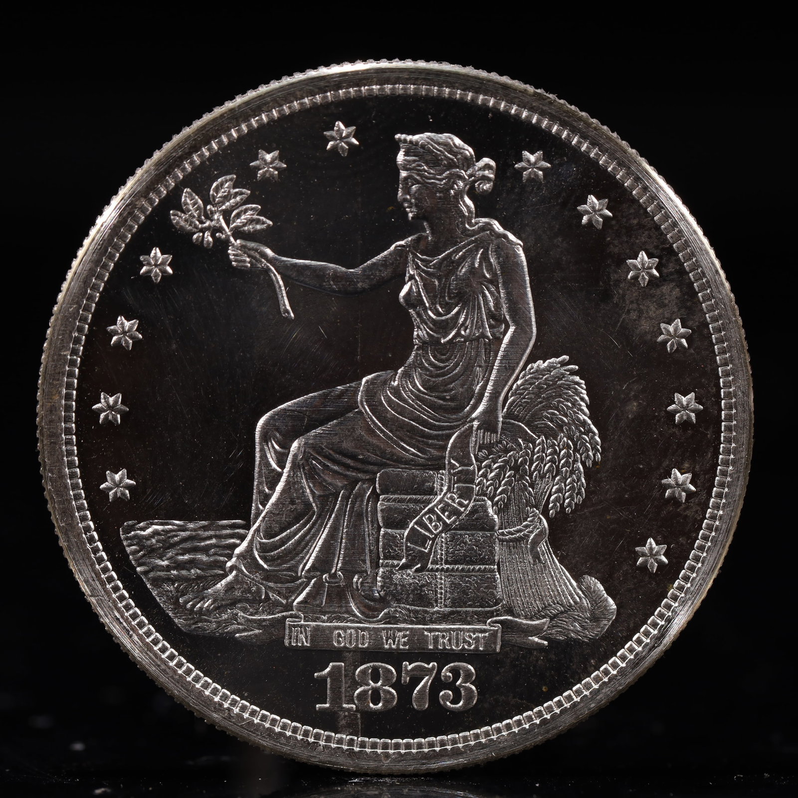 USA Trade Dollar 1873 Coin: American coin. Obverse: Liberty seated on a pedestal facing the sea to the left holding olive branches surrounded by 13 stars. IN GOD WE TRUST / LIBERTY / 1873. Reverse: An eagle holding branches with