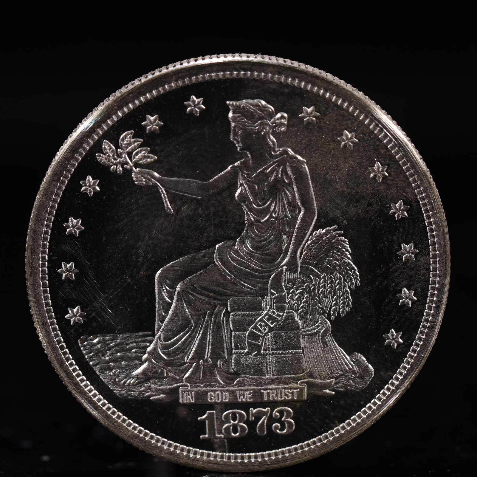 USA Trade Dollar 1873 Coin: American coin. Obverse: Liberty seated on a pedestal facing the sea to the left holding olive branches surrounded by 13 stars. IN GOD WE TRUST / LIBERTY / 1873. Reverse: An eagle holding branches with