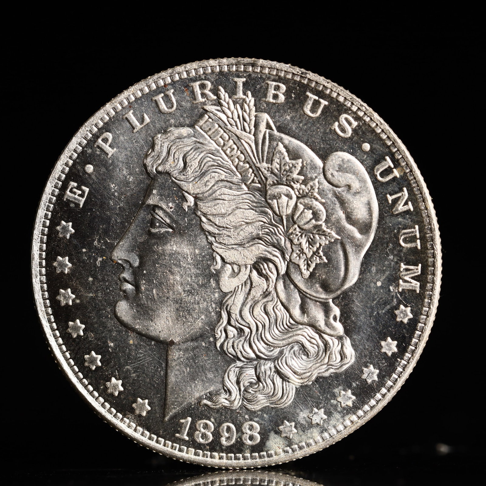 USA Morgan Dollar 1898 Coin: Obv: profile bust with date below and E PLURIBUS UNUM legend and stars around. Rev: eagle with In God we trust above within wreath with UNITED STATES OF AMERICA ONE DOLLAR legend. IN GOD WE TRUST / LI