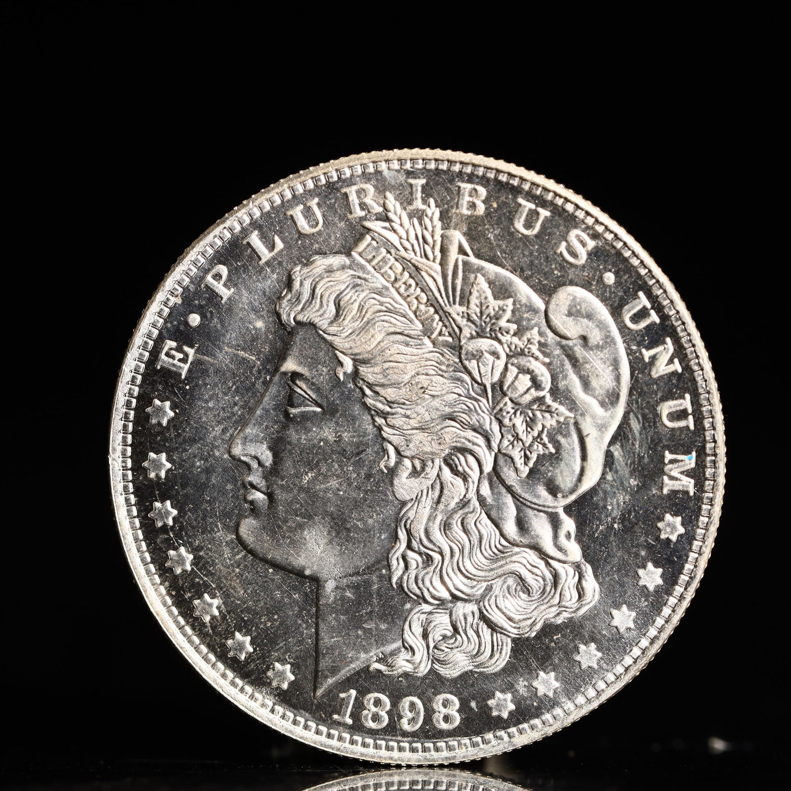 USA Morgan Dollar 1898 Coin: Obv: profile bust with date below and E PLURIBUS UNUM legend and stars around. Rev: eagle with In God we trust above within wreath with UNITED STATES OF AMERICA ONE DOLLAR legend. IN GOD WE TRUST / LI