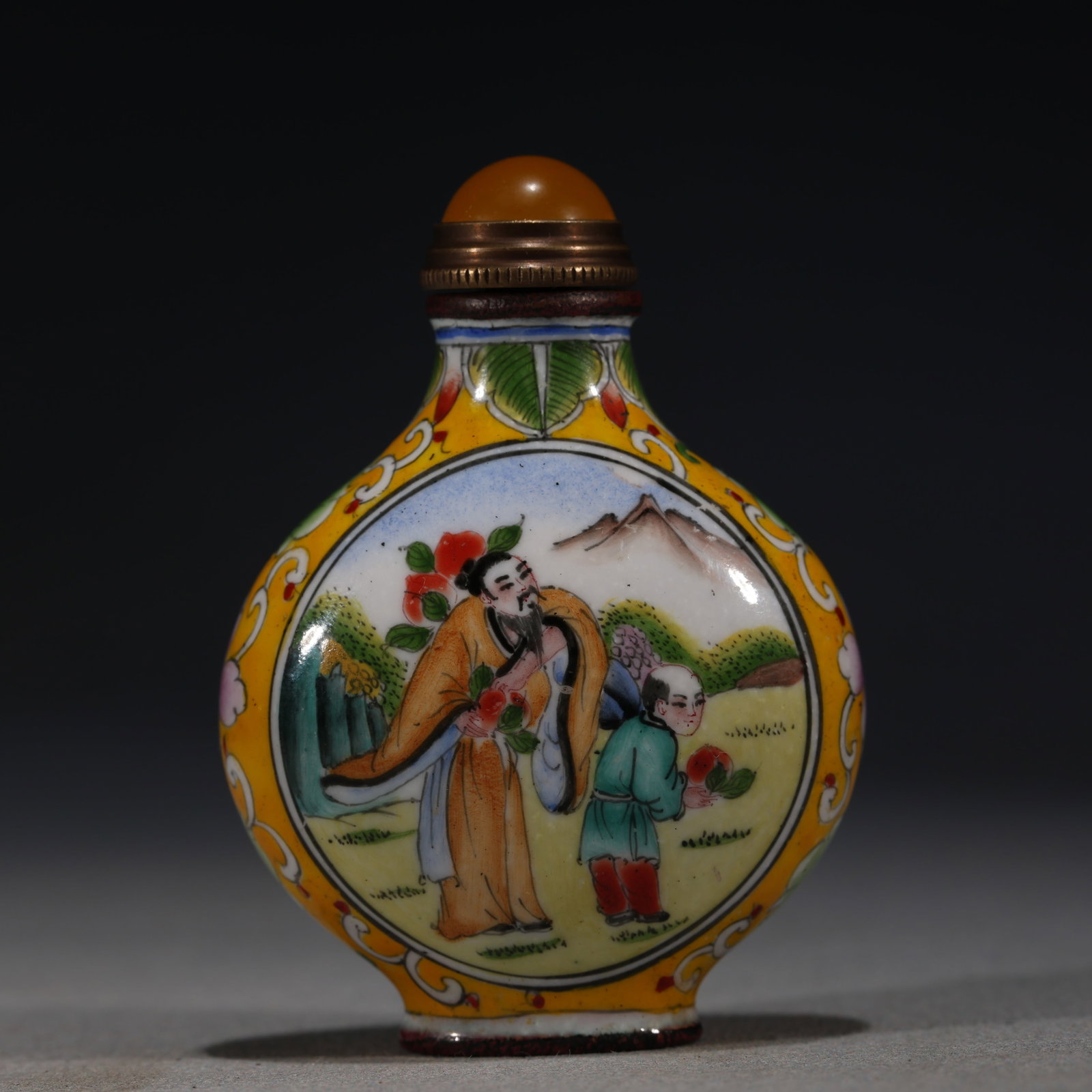 A Chinese Yellow-Ground Painted Enamel Snuff Bottle with Figures,Qianlong Mark: A Chinese painted enamel snuff bottle,decorated on both sides with figures in a garden setting holding flowers.Fitted with an amber stopper.The base bears a four-character mark reading(Qianlong Nian Z