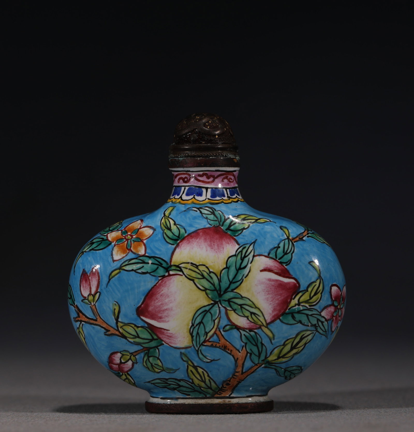 A Chinese Painted Enamel Snuff Bottle with Peaches and Squirrel,Qianlong Mark: A Chinese blue-ground painted enamel snuff bottle,decorated with a branch bearing two large peaches and a squirrel.Fitted with a bronze stopper.The base bears a four-character mark reading(Qianlong