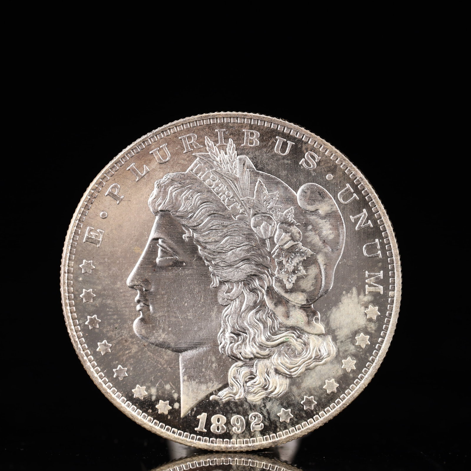 USA Morgan Dollar 1892 Coin: Obv: profile bust with date below and E PLURIBUS UNUM legend and stars around. Rev: eagle with In God we trust above within wreath with UNITED STATES OF AMERICA ONE DOLLAR legend. IN GOD WE TRUST / LI