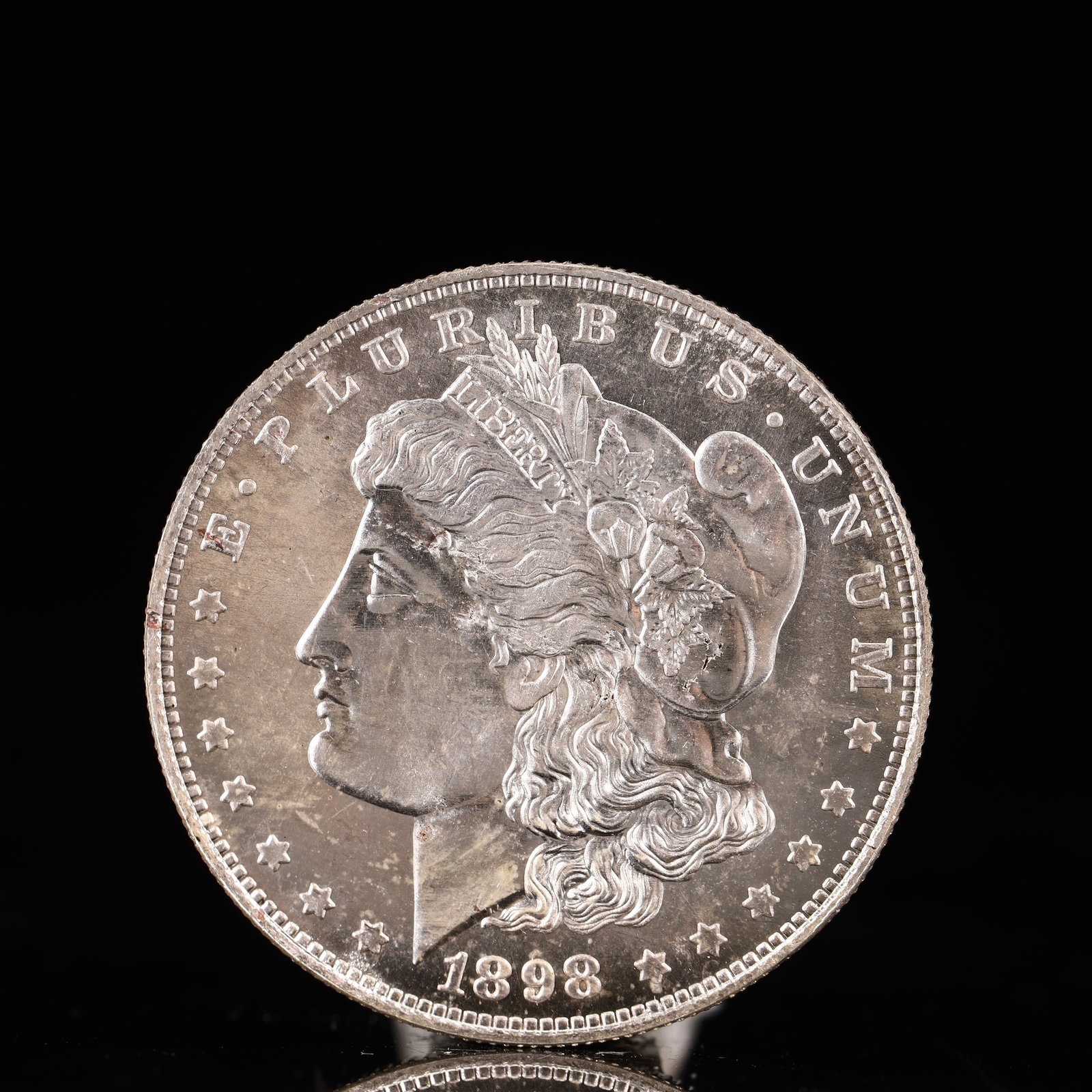 USA Morgan Dollar 1898 Coin: Obv: profile bust with date below and E PLURIBUS UNUM legend and stars around. Rev: eagle with In God we trust above within wreath with UNITED STATES OF AMERICA ONE DOLLAR legend. IN GOD WE TRUST /
