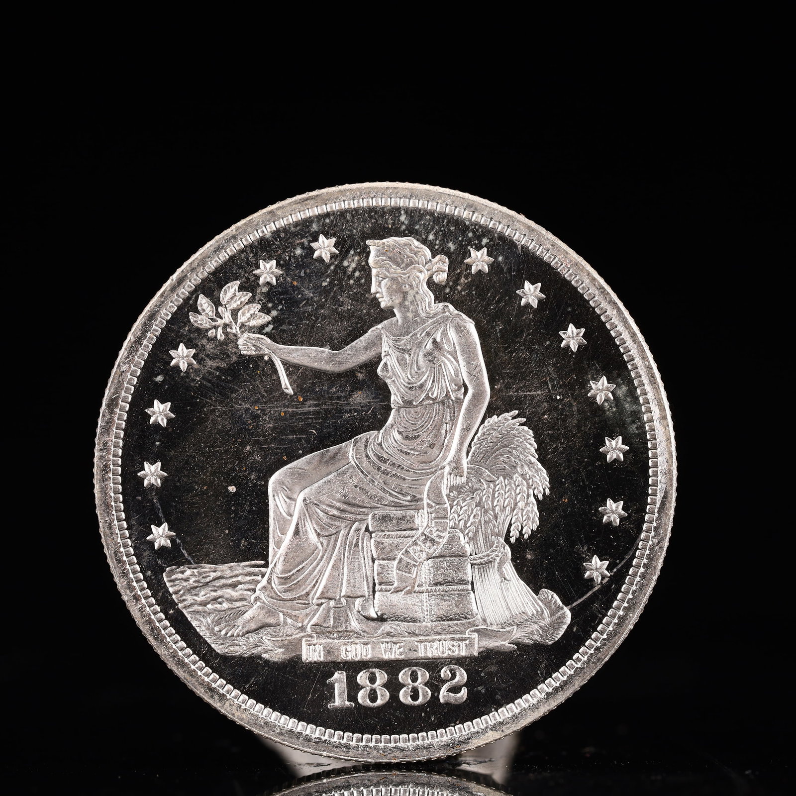 USA Trade Dollar 1882 Coin: American coin. Obverse: Liberty seated on a pedestal facing the sea to the left holding olive branches surrounded by 13 stars. IN GOD WE TRUST / LIBERTY / 1882. Reverse: An eagle holding branches with