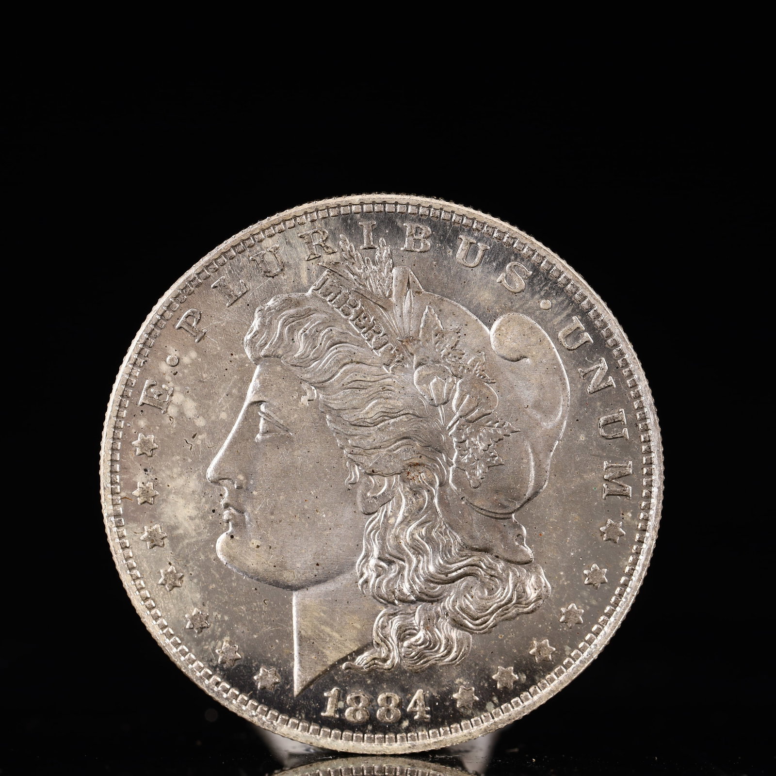 USA Morgan Dollar 1884 Coin: Obv: profile bust with date below and E PLURIBUS UNUM legend and stars around. Rev: eagle with In God we trust above within wreath with UNITED STATES OF AMERICA ONE DOLLAR legend. IN GOD WE TRUST / LI