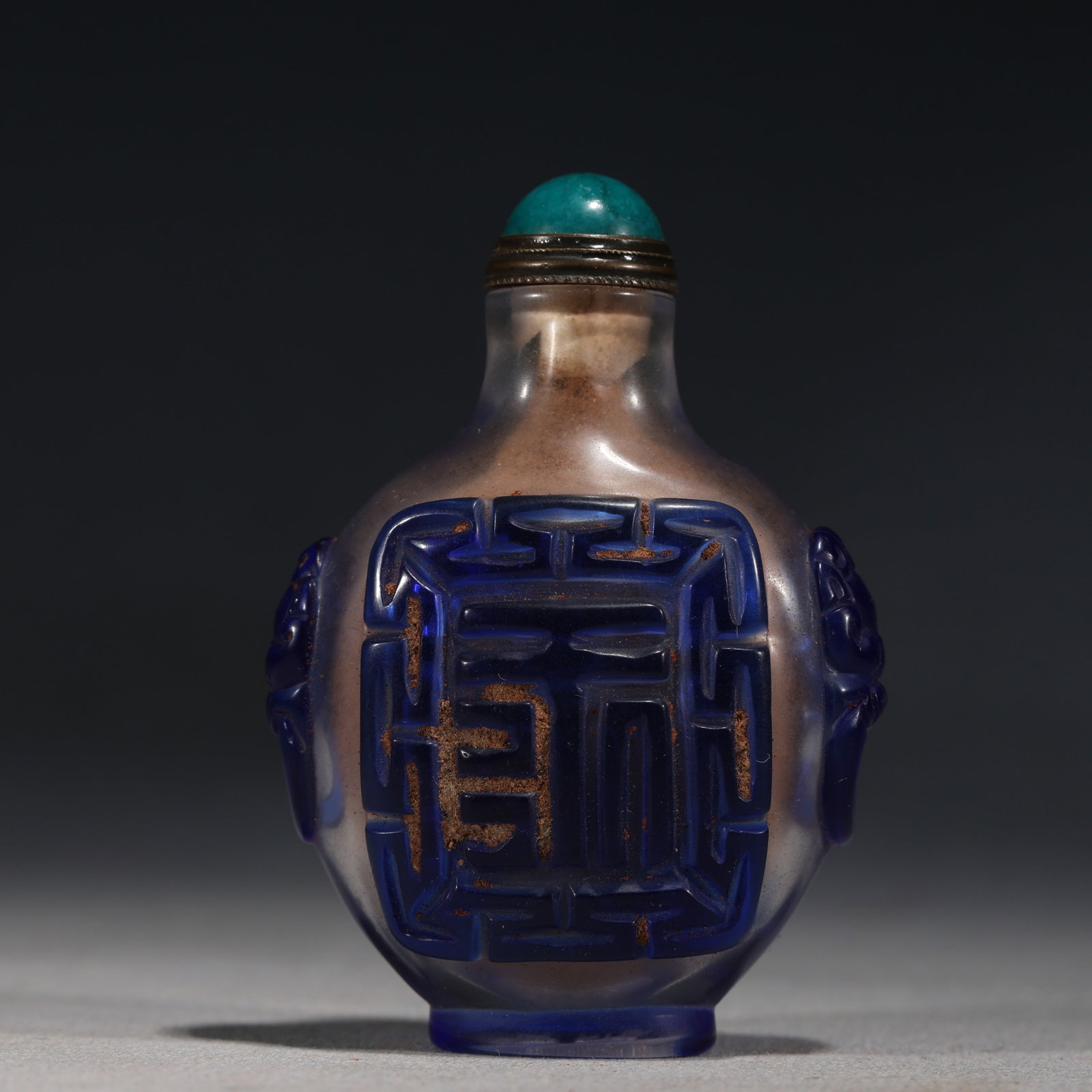 A Chinese Red Overlay Glass Snuff Bottle with Goldfish and Water Weeds,Qianlong Mark: A red overlay glass snuff bottle,deeply carved with goldfish swimming amidst water weeds and lotus.Fitted with a pink stopper.The base bears a four-character seal mark reading(Qianlong Nian Zhi).Size: