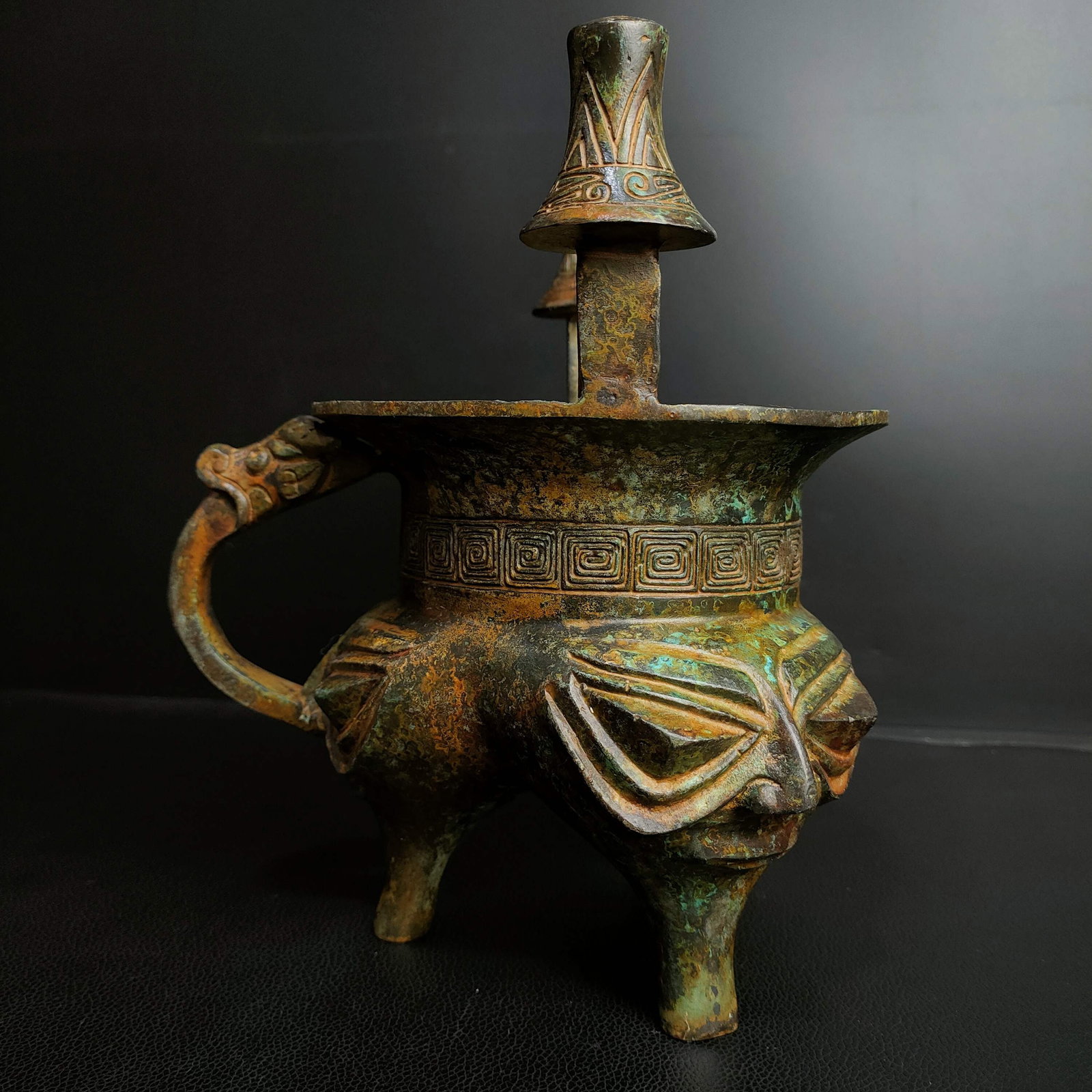 An Archaic Bronze Figure-Face Pattern Tripod Libation Cup: An Archaic Bronze Figure-Face Pattern Tripod Libation Cup,Qing Dynasty, China,Size:8.7inx7.1in,Weight:1800g青铜人面纹三足酒杯,中国