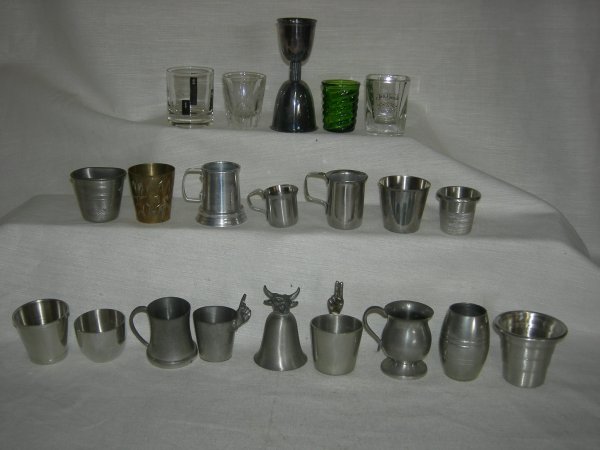 20 Jiggers: 20 Jiggers Including 10 Pewter: Godinger, 4 Sheffield, Woodbury, Cape Cod, American Guild; Etched Brass; Volrath Stainless; 4 Glass. Sizes Ranging From 1.5" Tall to 4.75" Tall.
