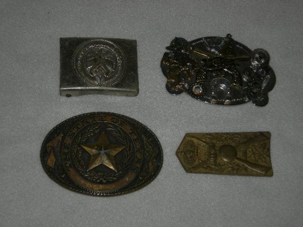 BELT BUCKLES, SWASTIKA: 1 Military Pin & 4 Belt Buckles Inc. Swastika w/Eagle & German Motto; Cowboy Theme w/Guns & Rhinestone; The State Of Texas w/Star; Military w/Rifles & Crown.