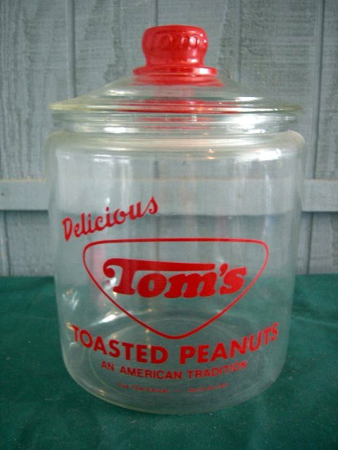 TOMS SALTED PEANUT JAR: Covered Glass Jar Advertising in Red "Delicious Toms Toasted Peanuts An American Tradition," Red Knob on Lid Embossed Toms, 10" Tall.