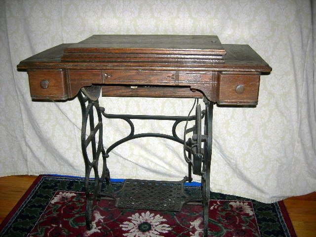 ANTIQUE SEWING MACHINE IN CABINET: Antique Sewing Machine In Cabinet w/Wrought Iron Stand & Treadle, 3 Drawers, 34" W x 18" D x 31 1/2" T.