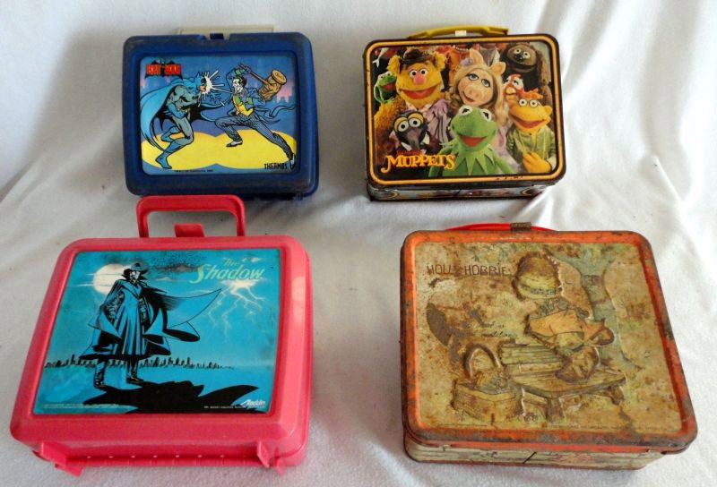VINTAGE LUNCHBOXES: Four Lunchboxes Including 2 Plastic: "The Shadow" Aladdin Industries 1994 and "Bat Man" TM & C DC Comics Inc. 1982; 2 Metal: "Holly Hobbie" Aladdin Industries and "Tim Henson's Muppet" 1979.