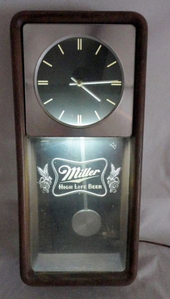 MILLER HIGH LIFE ADVERTISING CLOCK: "Miller High Life Beer" Electric Illuminated Clock, Lower Sign w/Pendulum Wood Grain Frame Stamped March 23rd 1982, 12" W X 25.75"T.