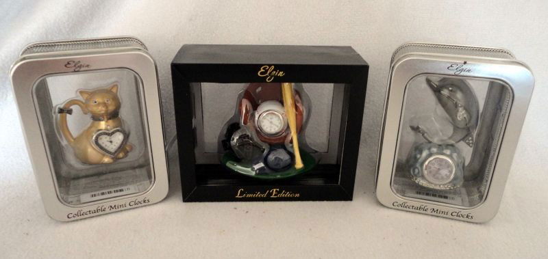 ELGIN MINATURE CLOCKS: 3 MIB Collectible Miniature Clocks, Including: Heart Shaped Mounted on Gold Cat, Baseball Shaped Inside Glove w/Face Guard, Helmet & Bat, Round Clock Mounted on Coral w/Silver Dolphin on Top, 2.5 –
