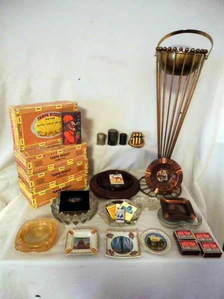 SMOKING MEMORABILIA: Lot Includes Smoking Stand w/Removable Ashtray, 4 Tampa Nugget Cigar Boxes, 8 Glass Ashtrays (1 in Wood Base), 3 Vintage Snuff Tins, Ladies Cigarette Case, Match Box Holder (Book/Bookends), 4 Souvenir
