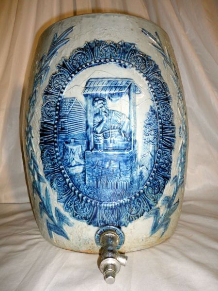 REBECCA AT THE WELL WATER COOLER: Large, Vintage, Embossed, Blue Stoneware Water Cooler, "Rebecca At The Well Front" & Floral Bouquet On Back, Metal Spout, Found in Pennsylvania, 12"D X 16.5"T.