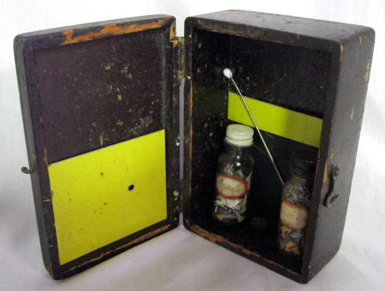 2005-2006 MIXED MEDIA ASSEMBLAGE: Untitled Assemblage: Wood Hinged Box With Latch, Painted Aluminum, Glass bottles With White & Black Screw Caps Containing Metal Shards And Circles, Scented, Glass Tipped Metal Rod And Pine Cone, Signe