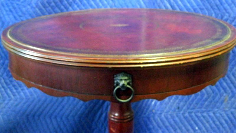 MACY'S DRUM TABLE: Mahogany Pedestal Drum Table, Macy's Mark & Paper Tag On Underside, Style 60M, Stamped Red Leather Top, Faux Drawer w/Decorative Lion Head Metal Pull, Metal Paw Caps & Casters, 22”D X 26.5”T.