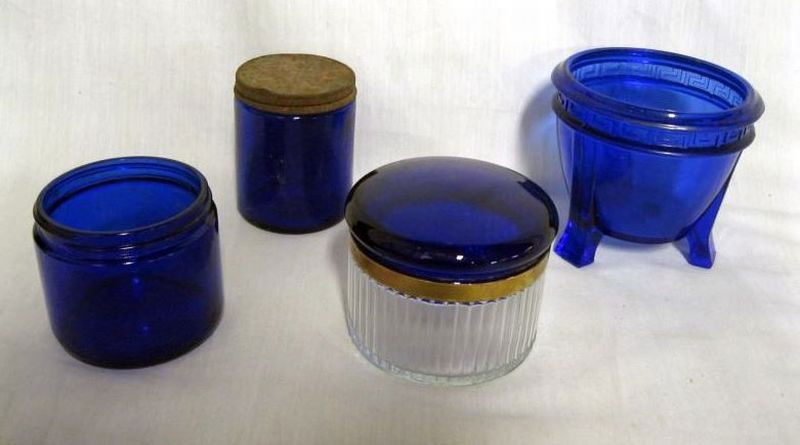 BLUE GLASS LOT: Lot Includes: 4”T Blue Jar w/Greek Key Design, Footed; 2.75”T Clear Glass Panel Side Jar w/Cobalt Blue Lid w/Gold Stripe; 3.75”T Jar w/Metal Lid, Marked M & 3”T Open Jar, Marked Noxzema.