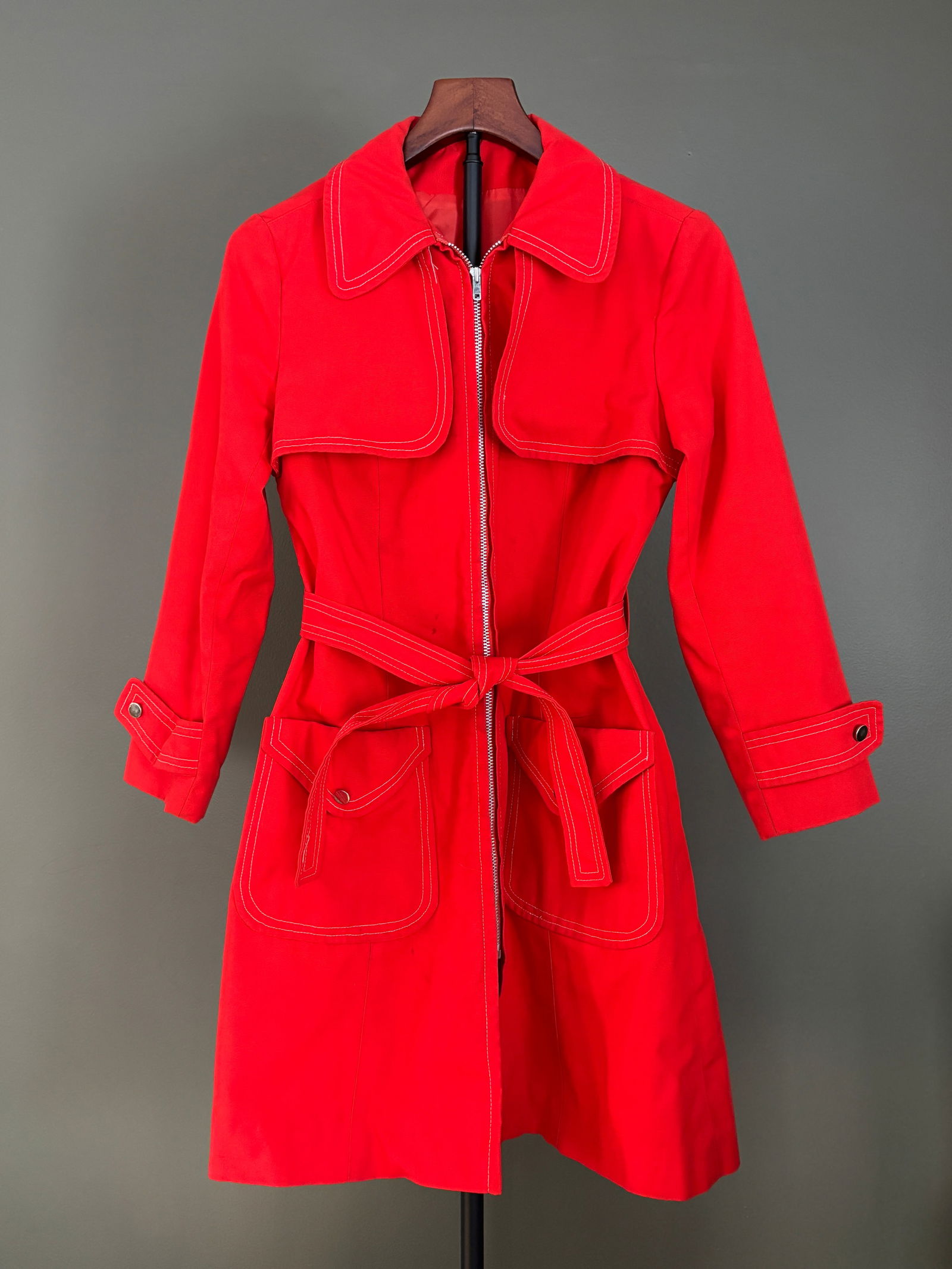 Vintage Women's Red Belted Boston Forecaster Trench Coat, XS-S: Bold red mod-style mid-century coat featuring a clean, tailored silhouette with high-contrast white topstitching throughout, zip-front closure, wide collar with storm flap detail, self-tie waist belt,