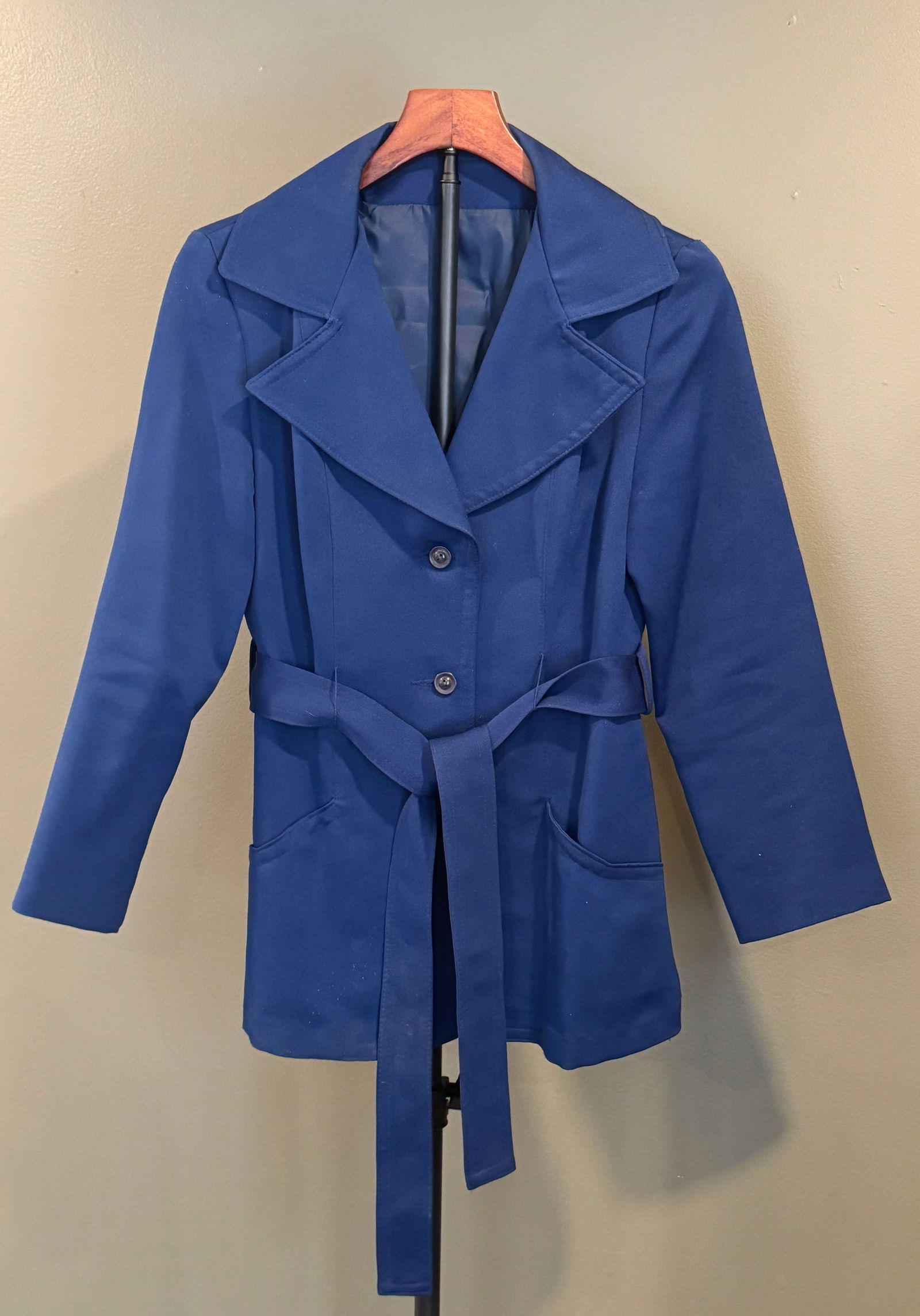 Vintage Blue Belted Jacket: Vintage women's jacket in a rich cobalt blue, featuring wide lapels, a button-front closure, and a self-tie belt at the waist. Tailored silhouette with front pockets. Labeled for machine wash on delic