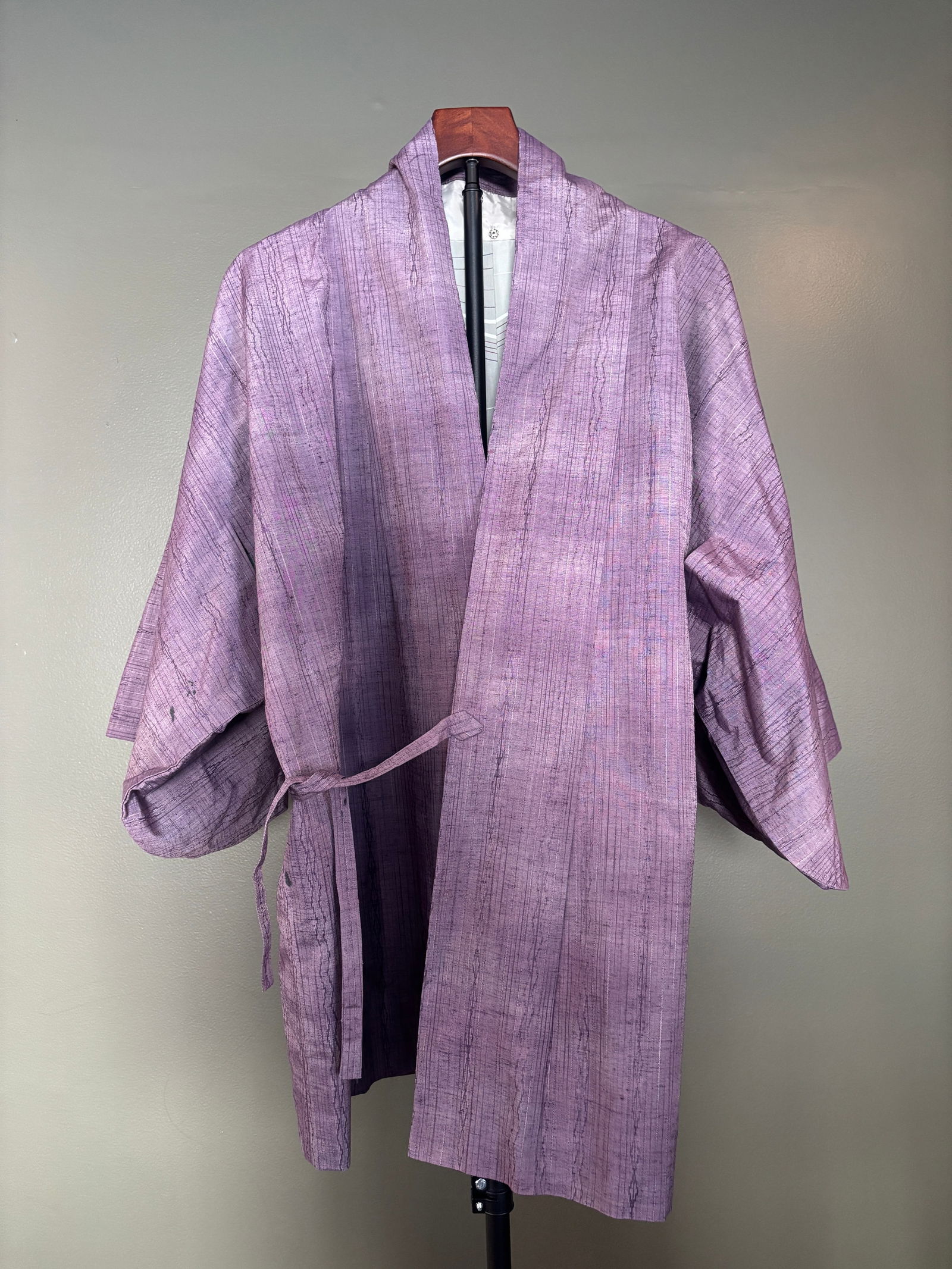 Vintage Japanese Lavender Silk Kimono-Style Robe with Tie Belt: Vintage Japanese kimono-style robe in a soft lavender hue, crafted from lightweight silk with pronounced slub texture and vertical striations throughout. Wrap-front construction with wide sleeves and
