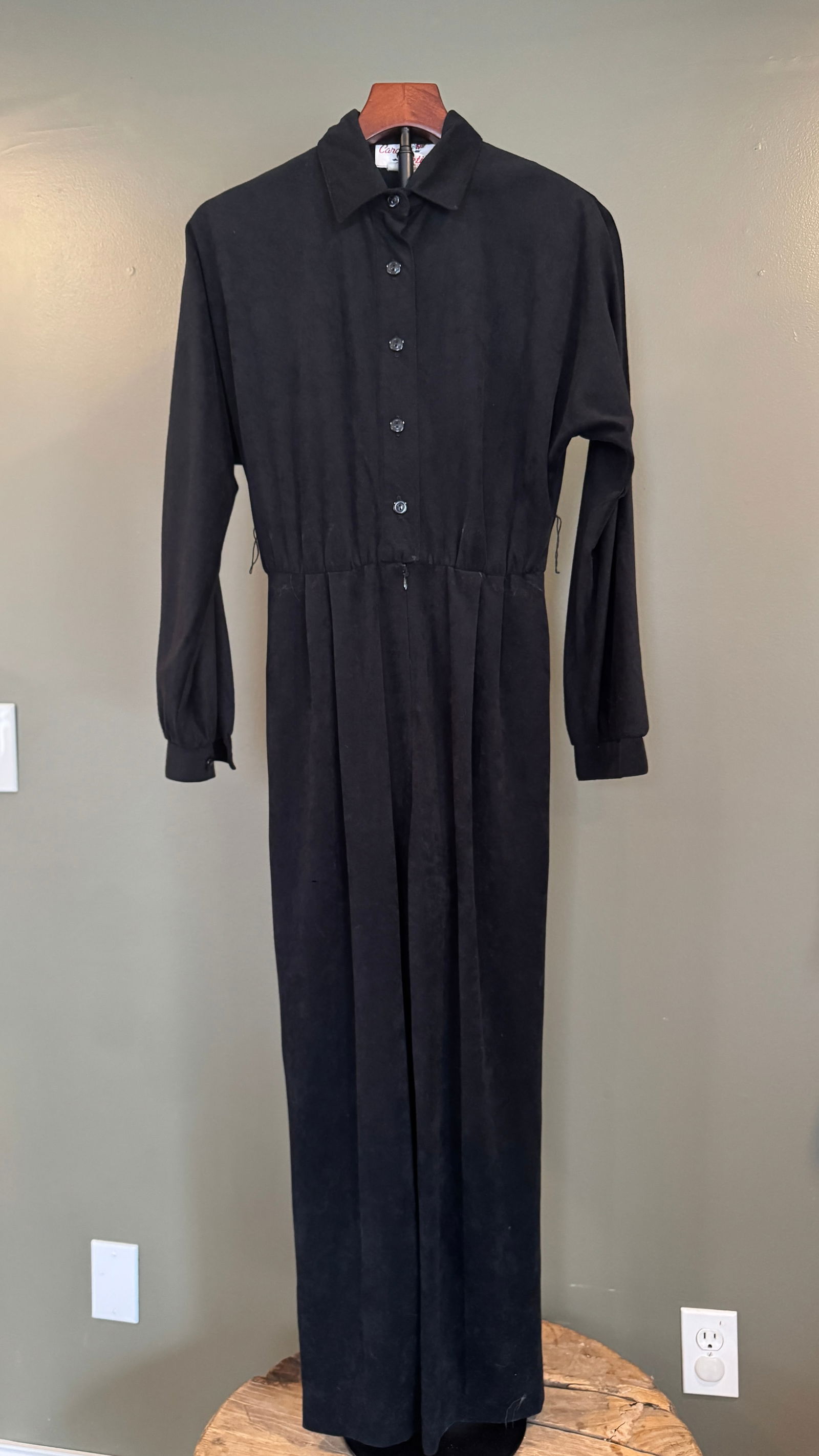 Carmen Petite Black Long-Sleeve Jumpsuit, USA: Vintage black jumpsuit by Carmen Petite, featuring a button-front bodice, pointed collar, long sleeves with cuffed wrists, and softly pleated legs. Elasticized waist creates a flattering, tailored sil