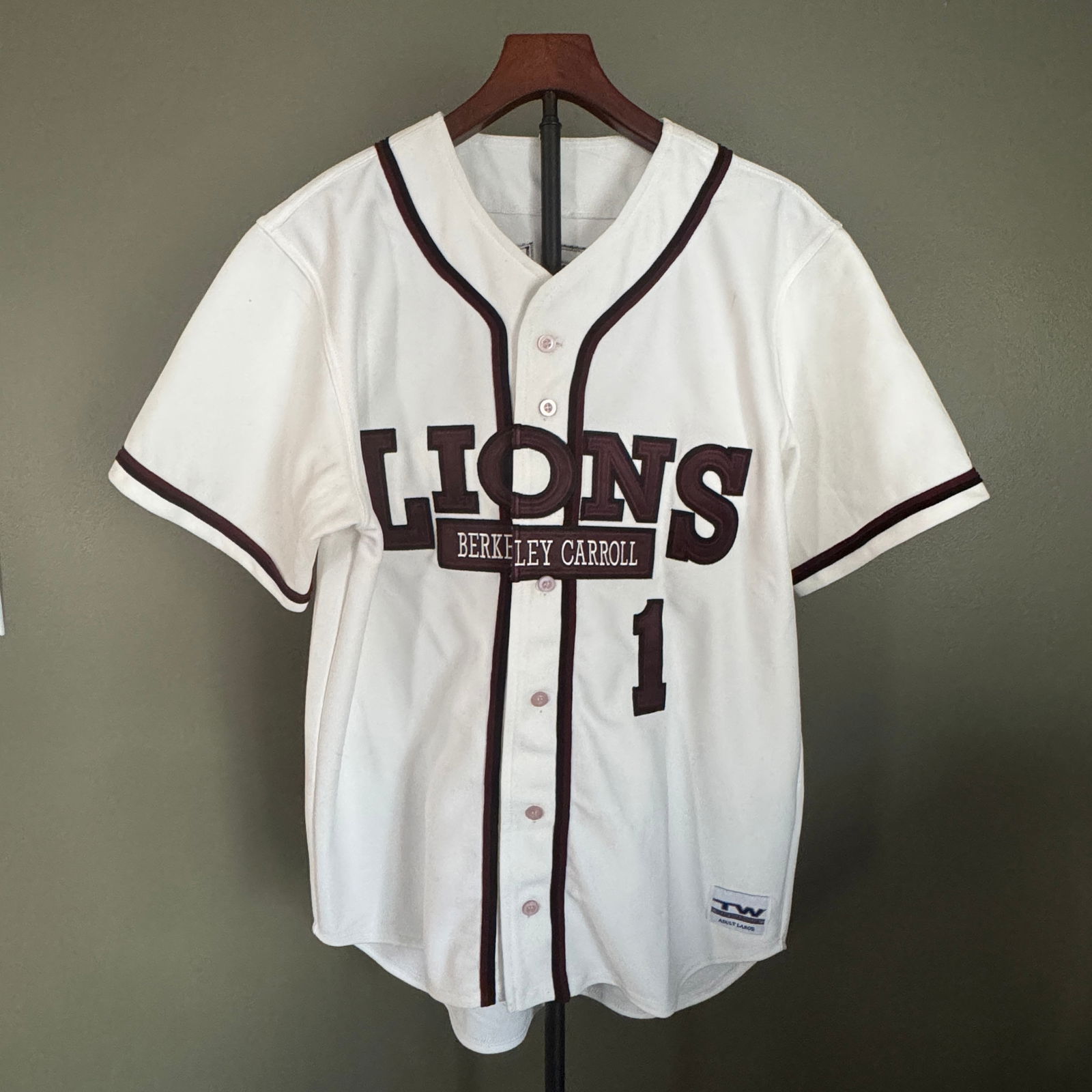 Berkley Carroll Lions Baseball Jersey, No. 1 - Team Warehouse, Adult Large: Classic white baseball jersey featuring "Lions "“ Berkley Carroll" lettering at front and player name Bartier with number 1 at back. Button-front design with contrasting maroon trim. Manuf
