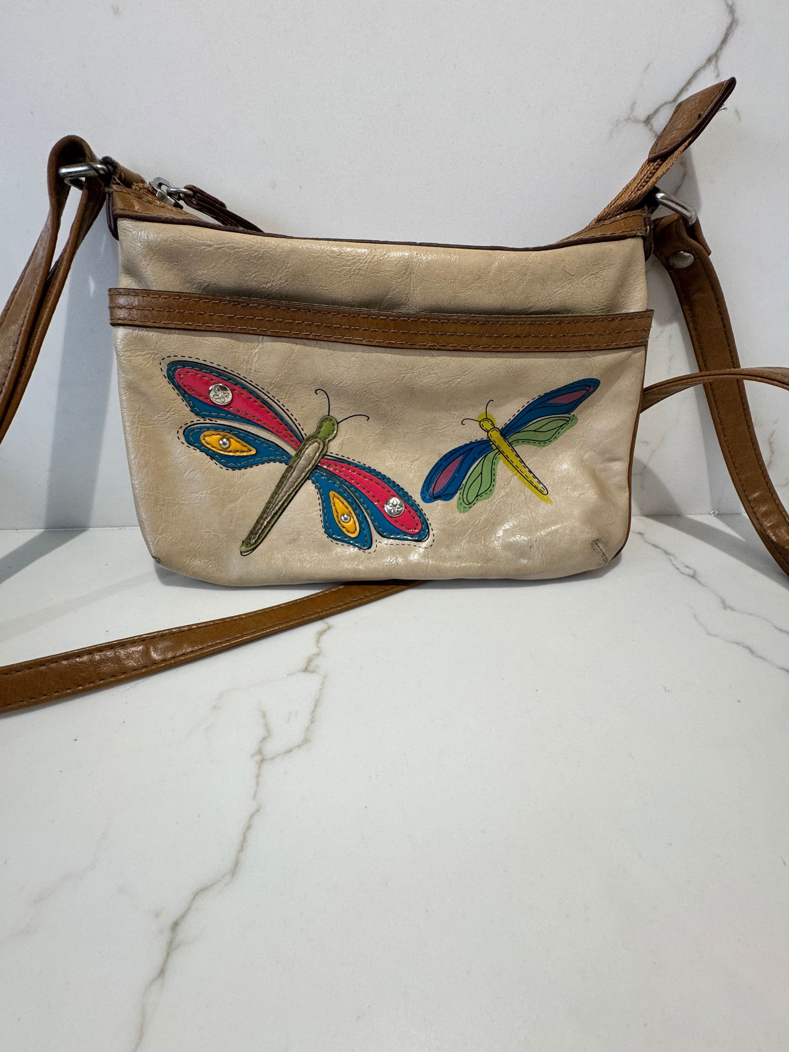 Relic Embellished Faux Leather Crossbody Bag: A compact crossbody bag by Relic, crafted in taupe-toned faux leather with contrasting brown trim. The exterior features colorful appliquÃ© dragonfly motifs accented with small rhinestone de
