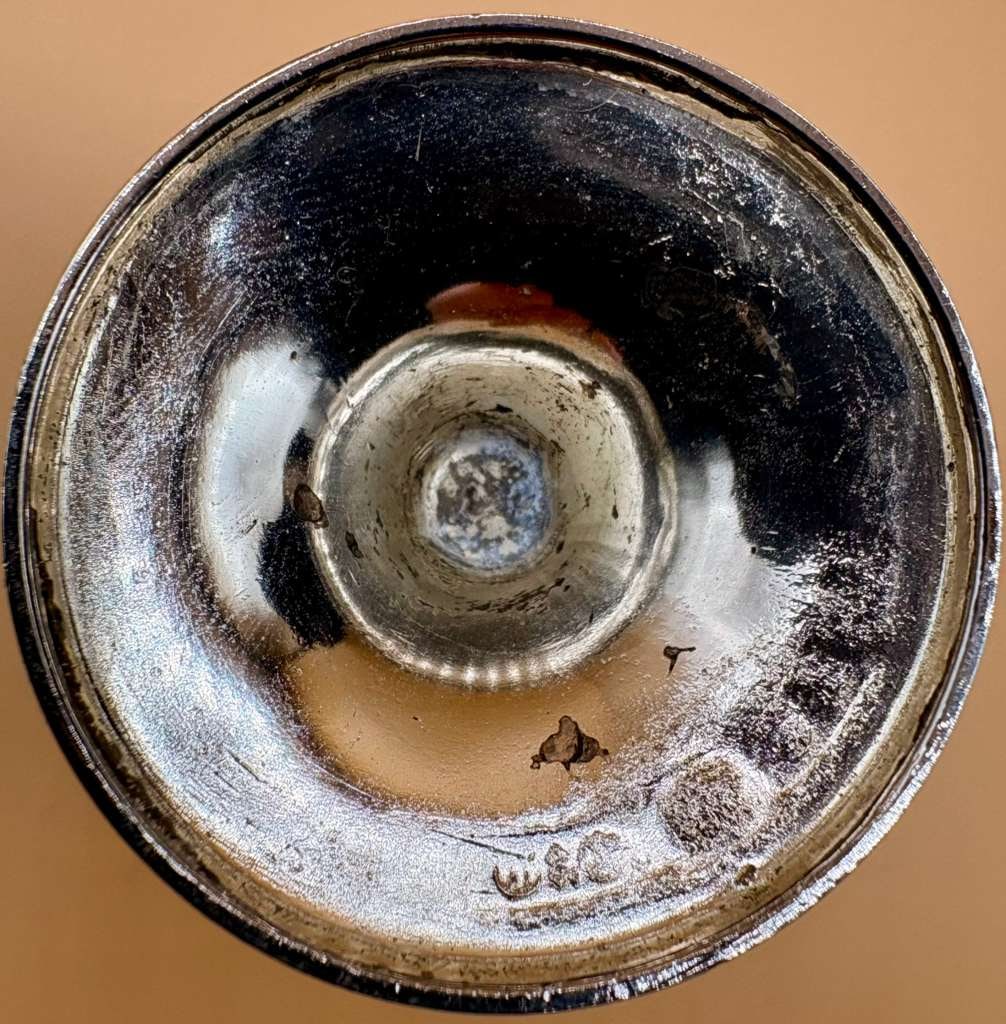 Vintage Silver-Tone Metal Candlestick with Classical Relief Decoration: Decorative vintage candlestick crafted in silver-tone metal, featuring a solid circular base with classical relief ornamentation, including scrolling and floral motifs. The surface exhibits natural pa