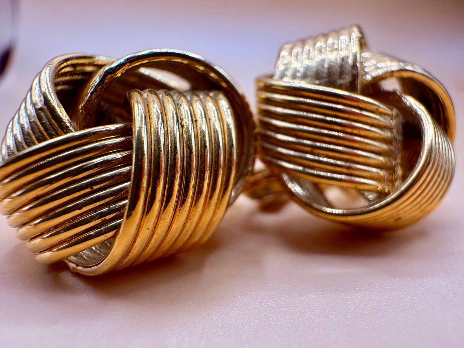 Vintage Trifari Gold-Tone Clip-On Knot Earrings: Pair of vintage clip-on earrings by Trifari, featuring a sculptural knot design composed of ribbed, intertwined gold-tone metal elements. The form presents a bold, dimensional appearance with a classi