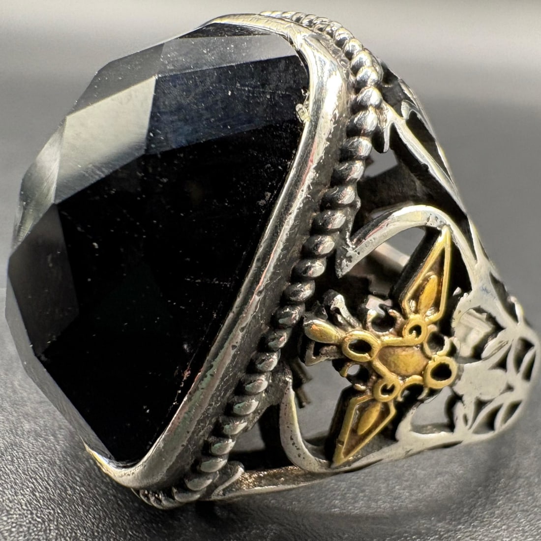 Vintage Black Agate Sterling Silver Ring: Vintage jewelry ring featuring a faceted black agate stone in a rectangular/elongated shape. The stone is set in a raised mounting with decorative detailing visible around the bezel. The band is craft