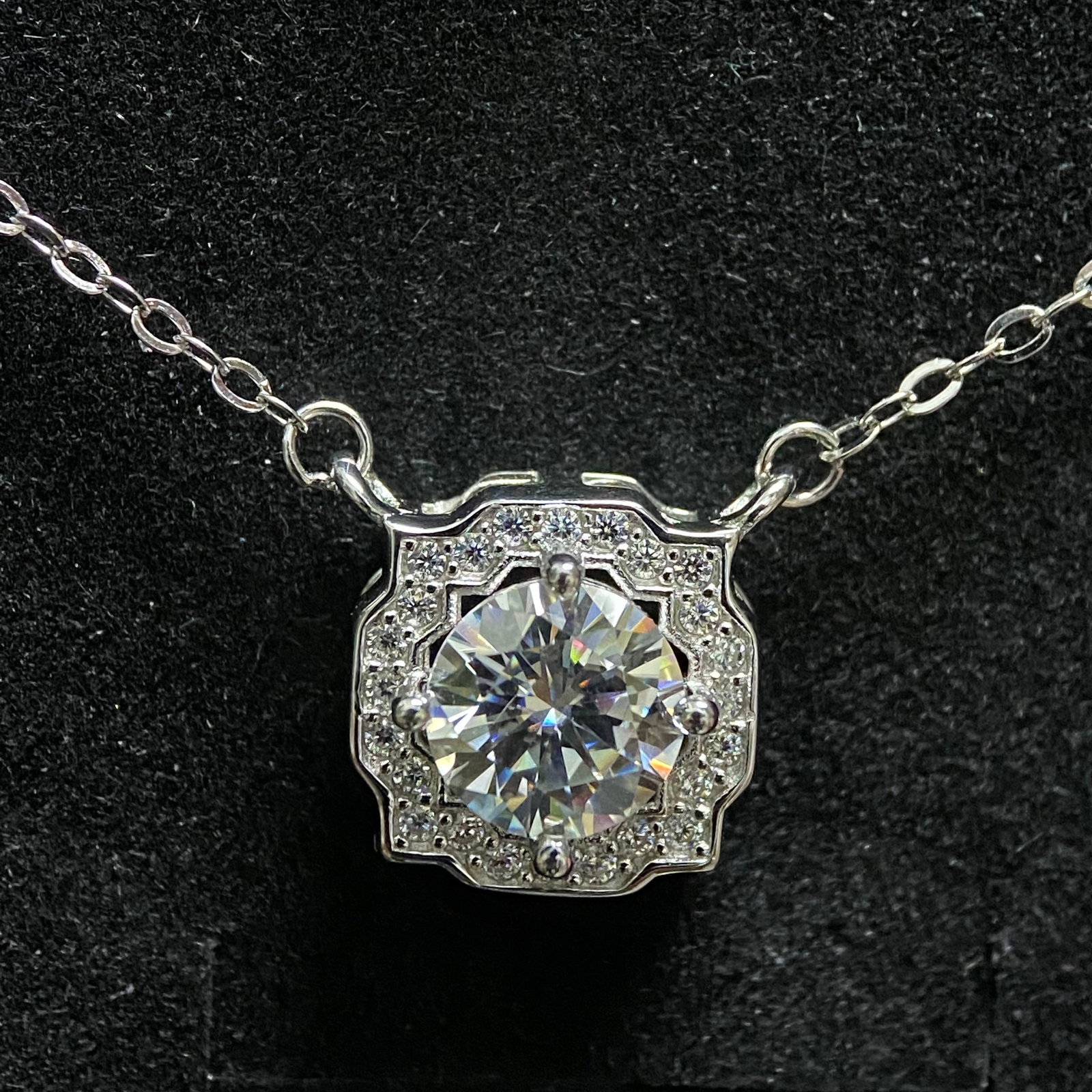 Vintage-Style Moissanite Geometric Pendant Necklace: An exquisite necklace featuring a central round brilliant-cut moissanite set within a sophisticated geometric halo. The pendant's structured design and milgrain-style detailing evoke a classic vintage